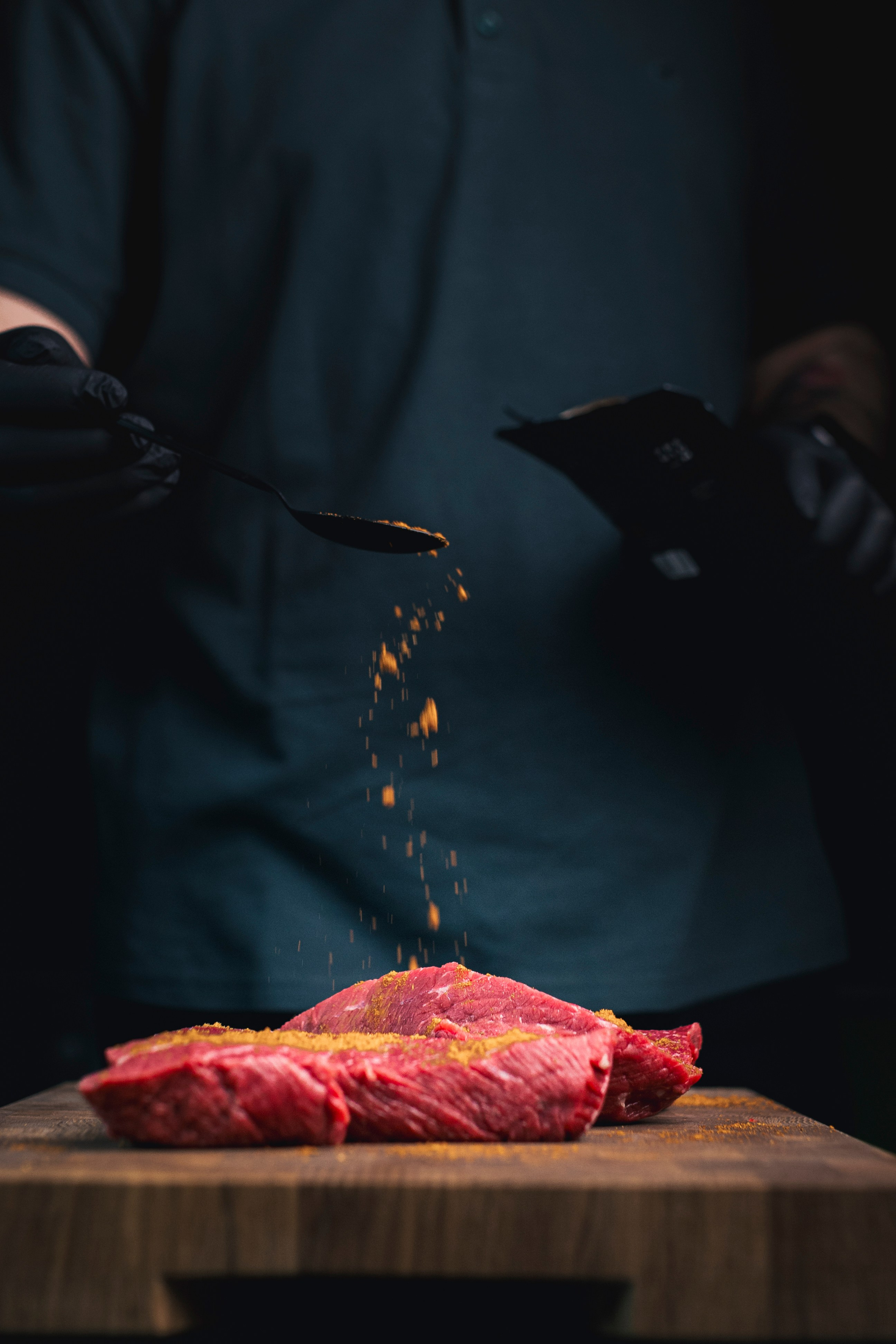 мужчина приправляет мясо 