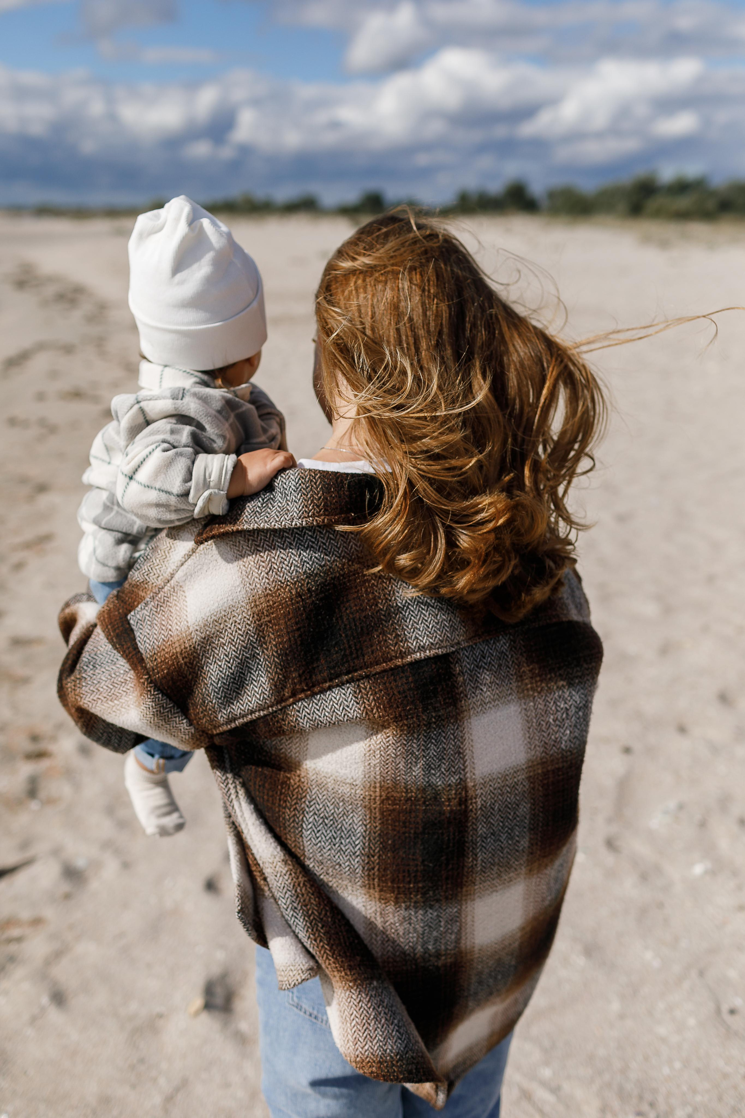 Мама с дочкой гуляет по берегу песчаного пляжа, черного моря.