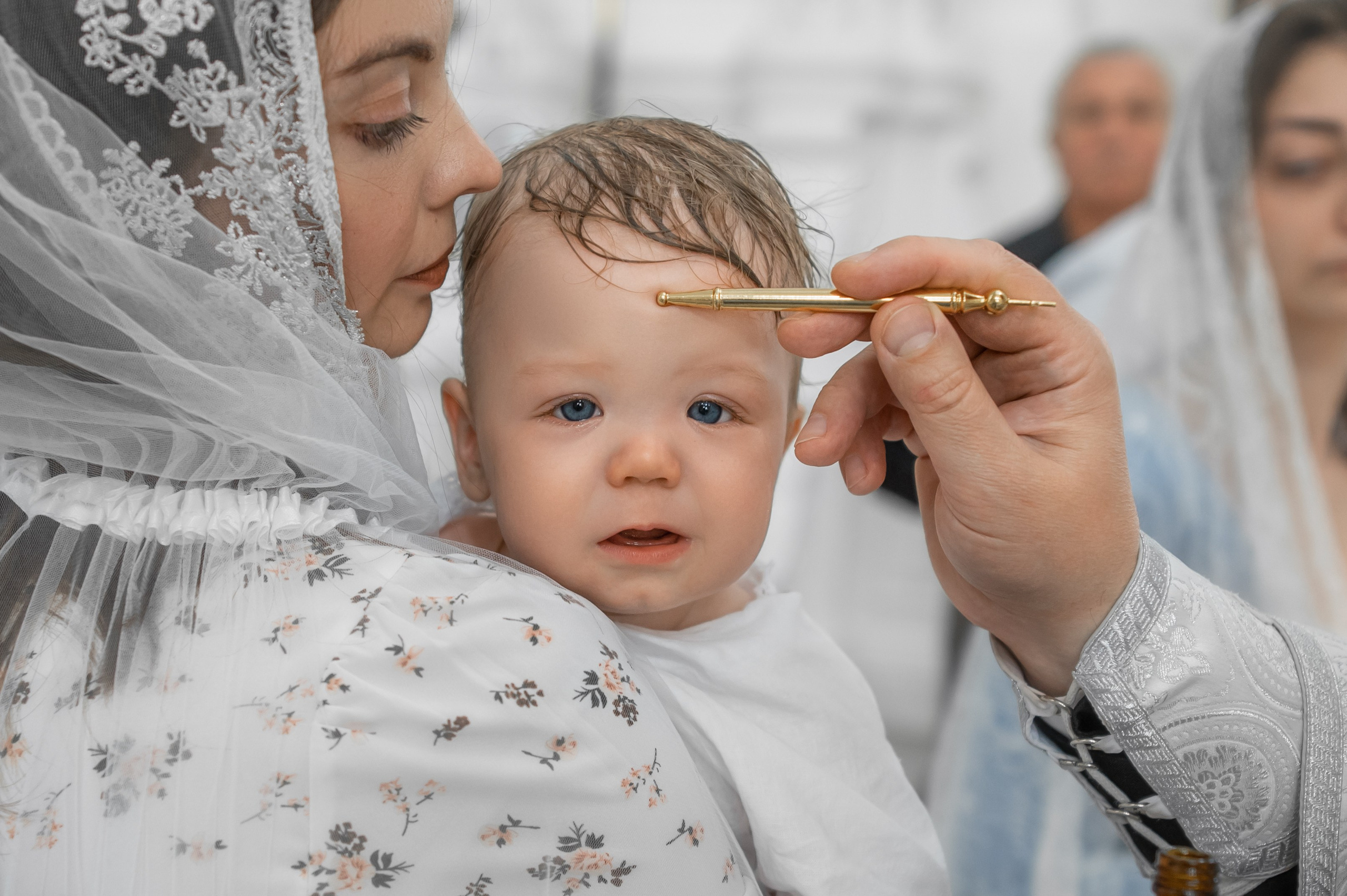 малыша помазывают елеем во время крещения