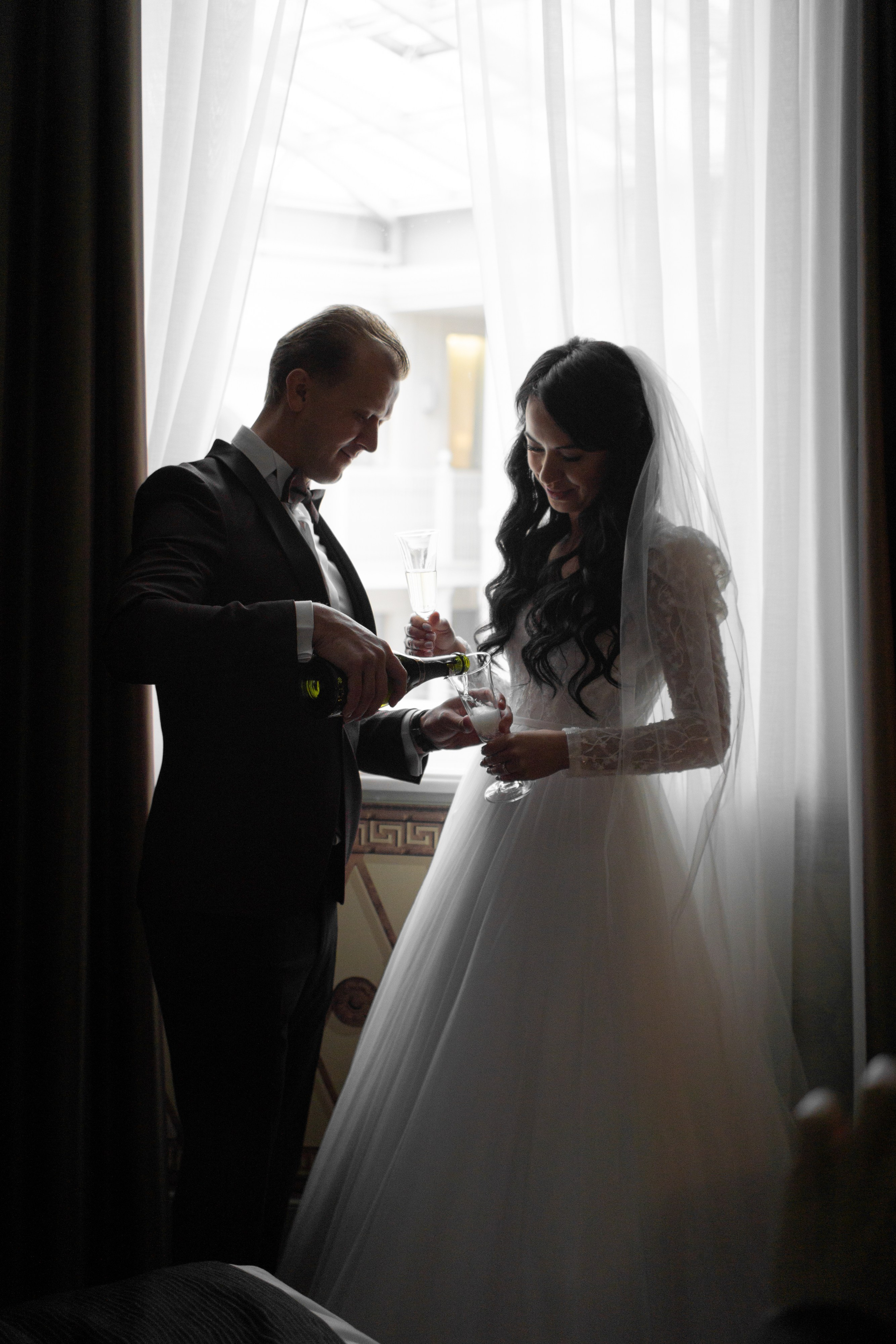 жених наливает шампанское в номере в отеле Индиго на свадебной фотосессии