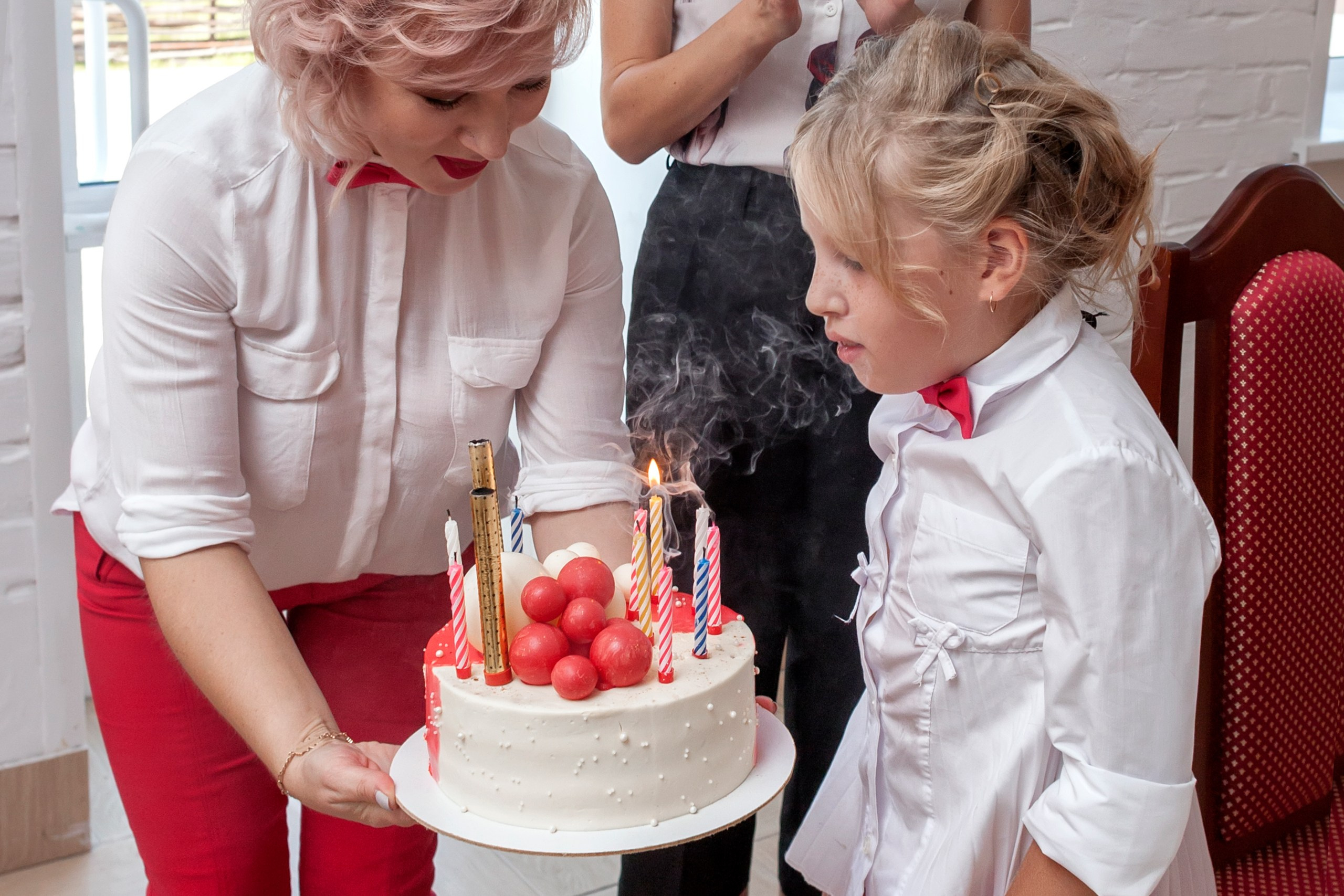 Именинница задувает свечи на торте, фотосъёмка детских мероприятий.