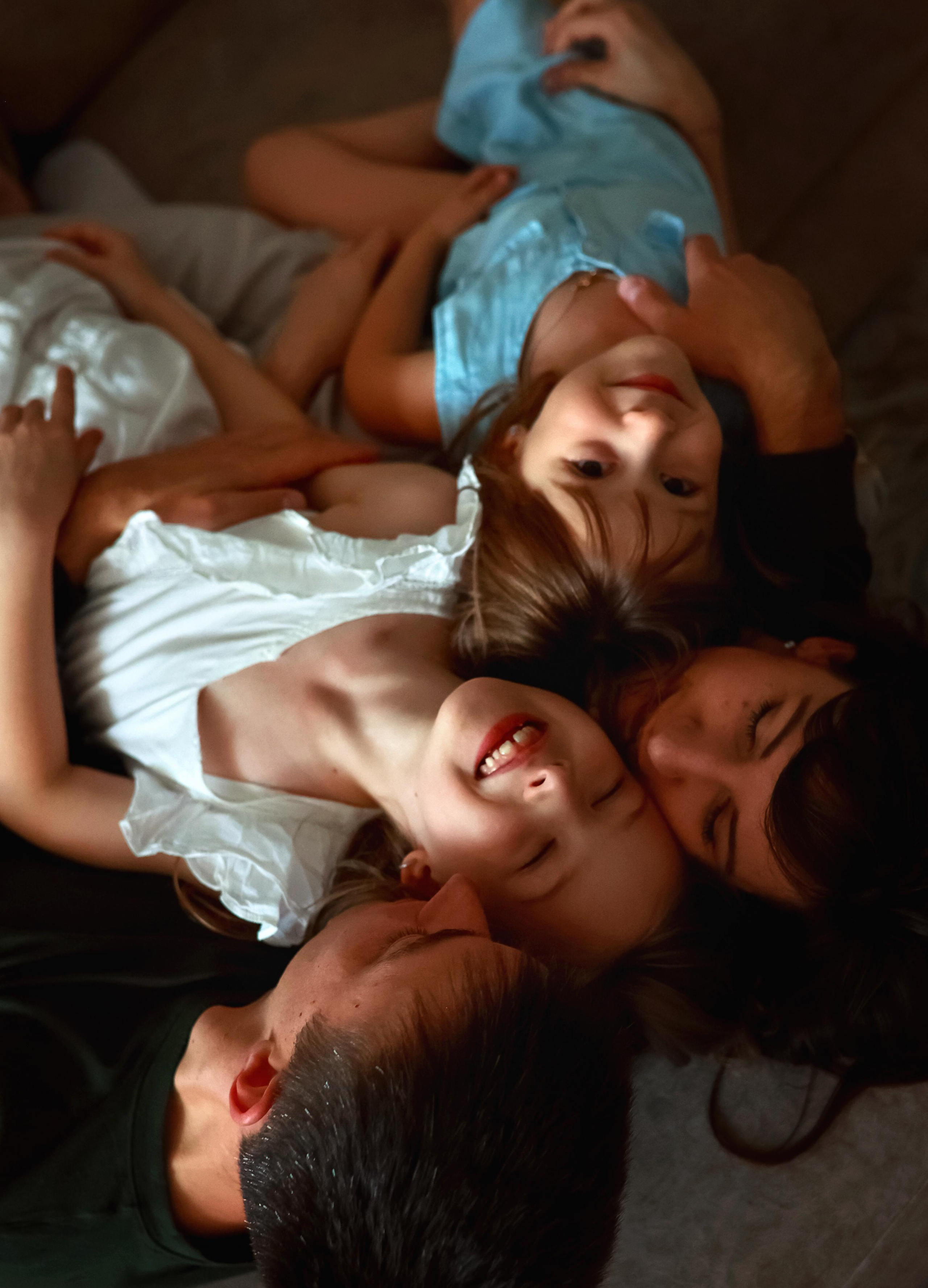 Lifestyle домашняя фотография счастливой семьи. Родители и дети весело резвятся на кровати.