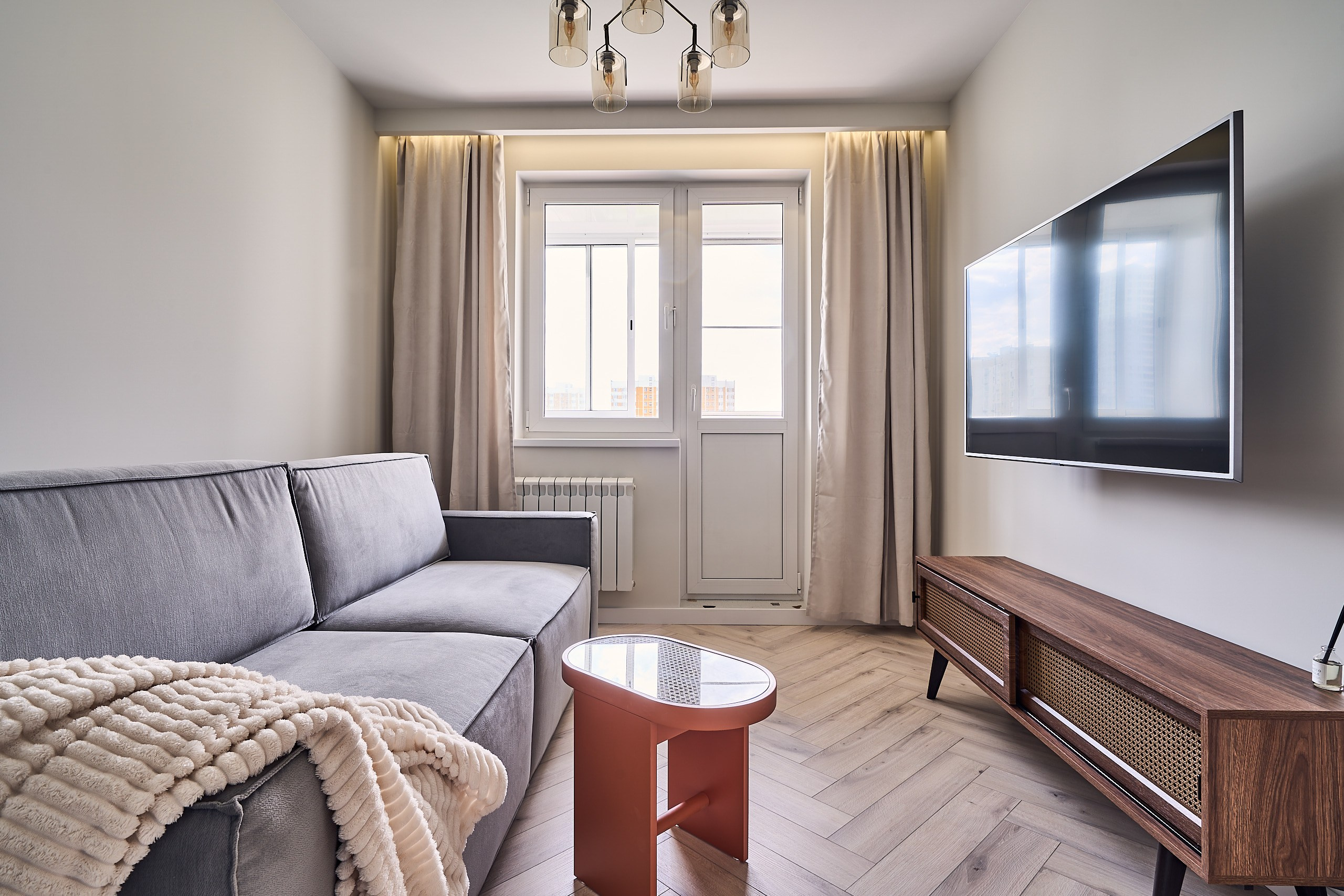 Интерьерное фото фронтального плана гостиной в квартире на Северо-Западе столицы, вид на окно и балконную дверь