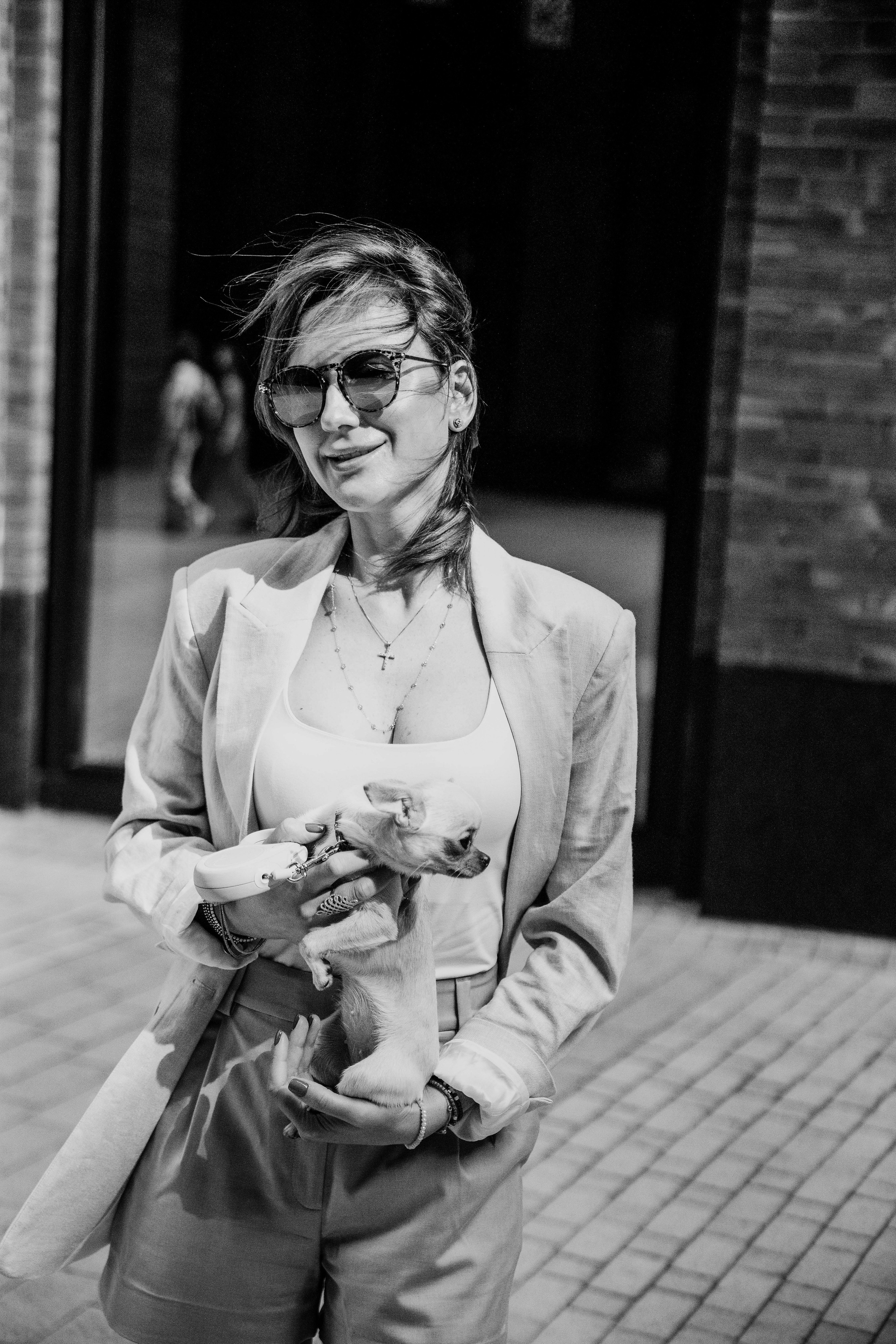 Красивая молодая мама гуляет по улицам Москвы со своим питомцем собачкой и улыбается 