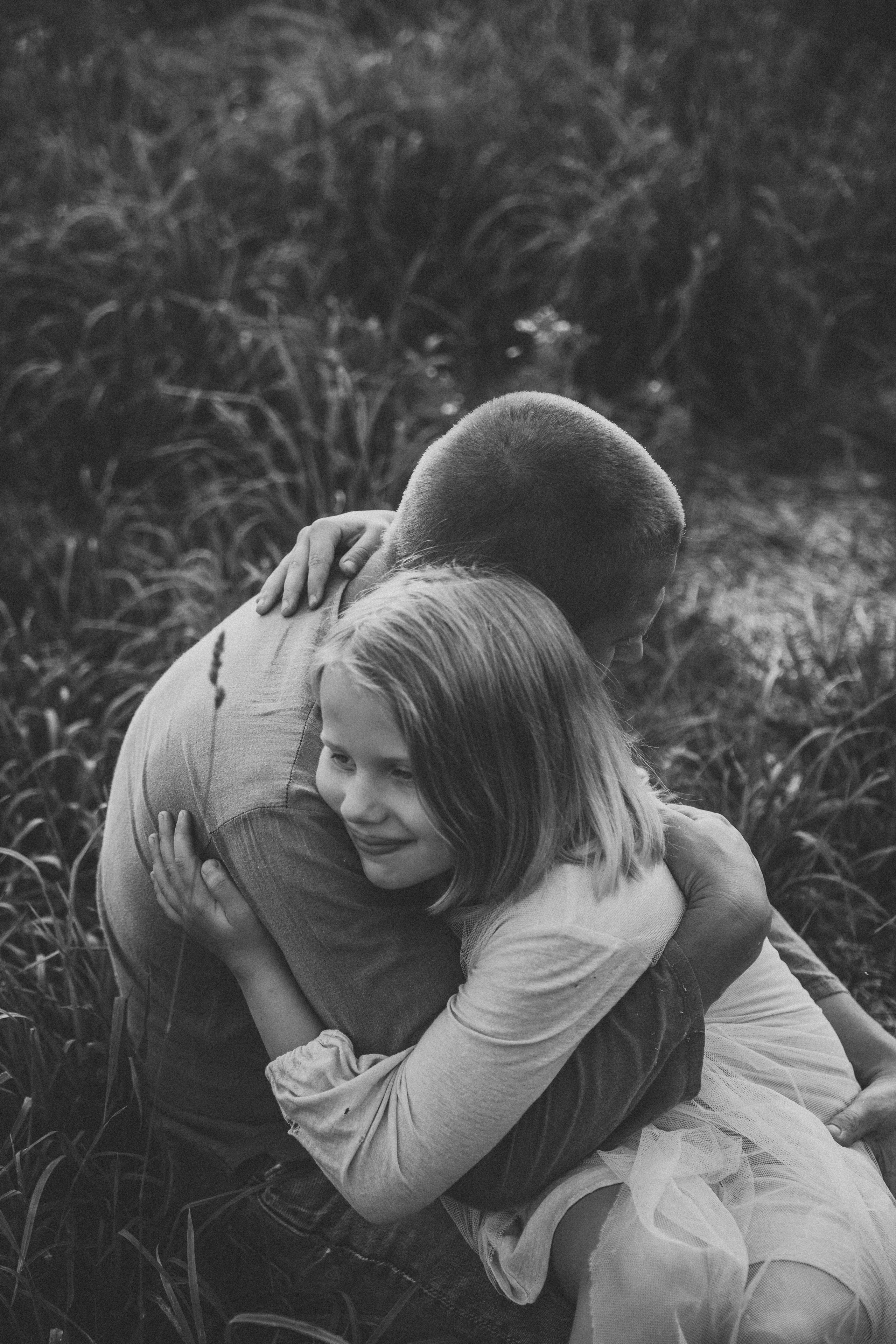 молодой папа  обнимает свою маленькую дочку летом на закате