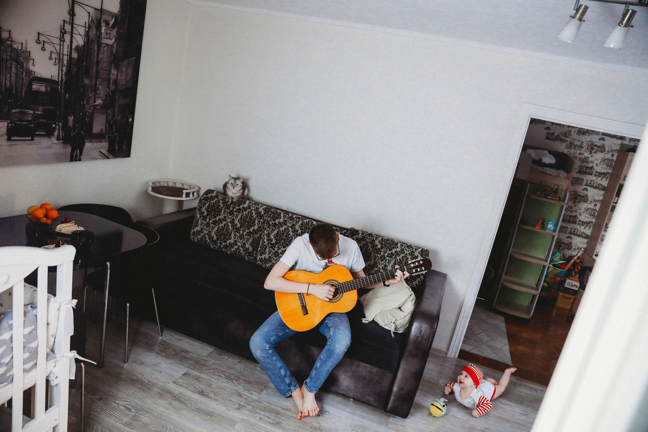 Молодой человек играет на гитаре у себя дома