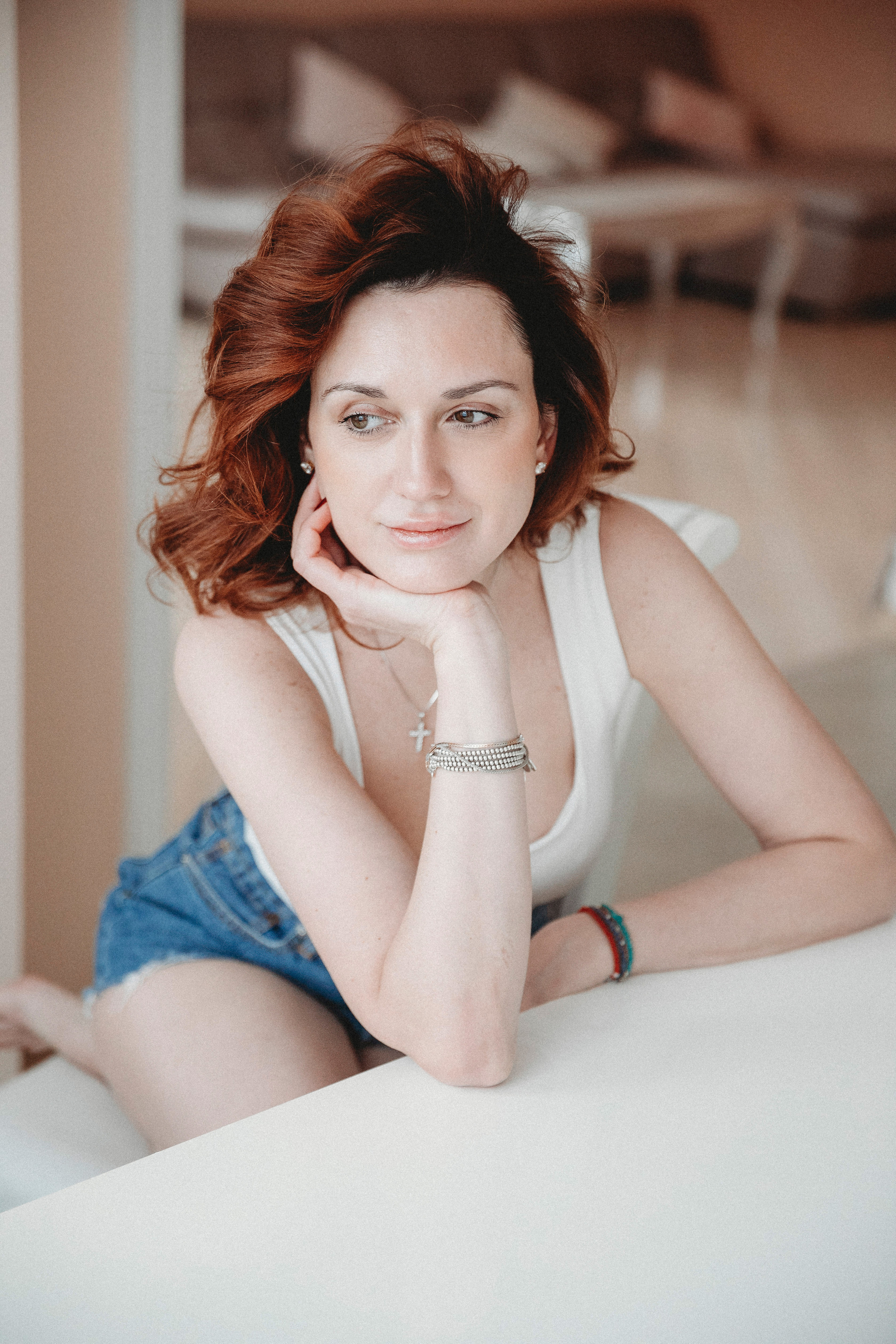 красивая девушка сидит на стуле на кухне у себя дома и смотрит в окно