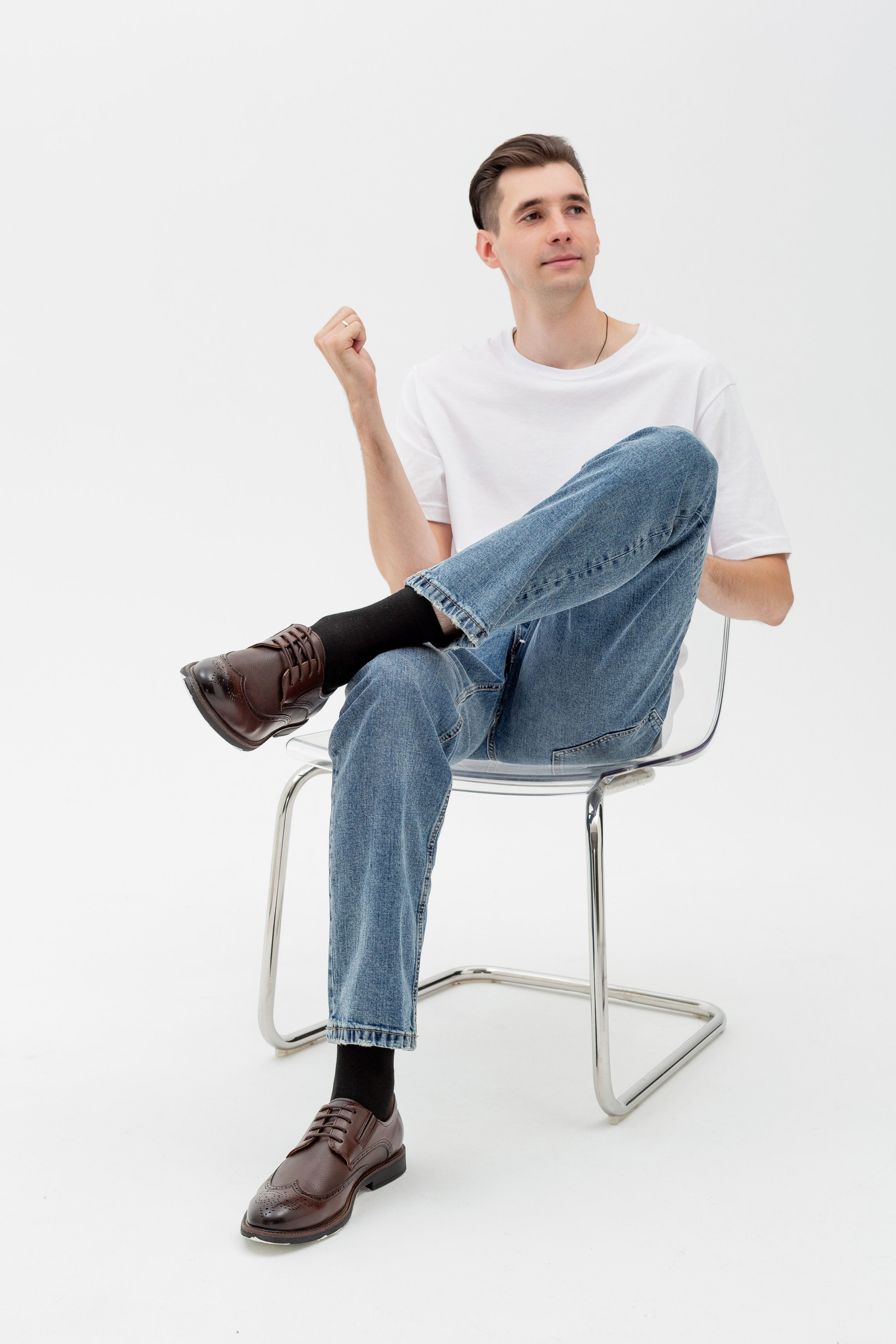 Студийный портрет мужчины сидящем на стуле, ростовой портрет, в белой футболке и джинсах на белом фоне