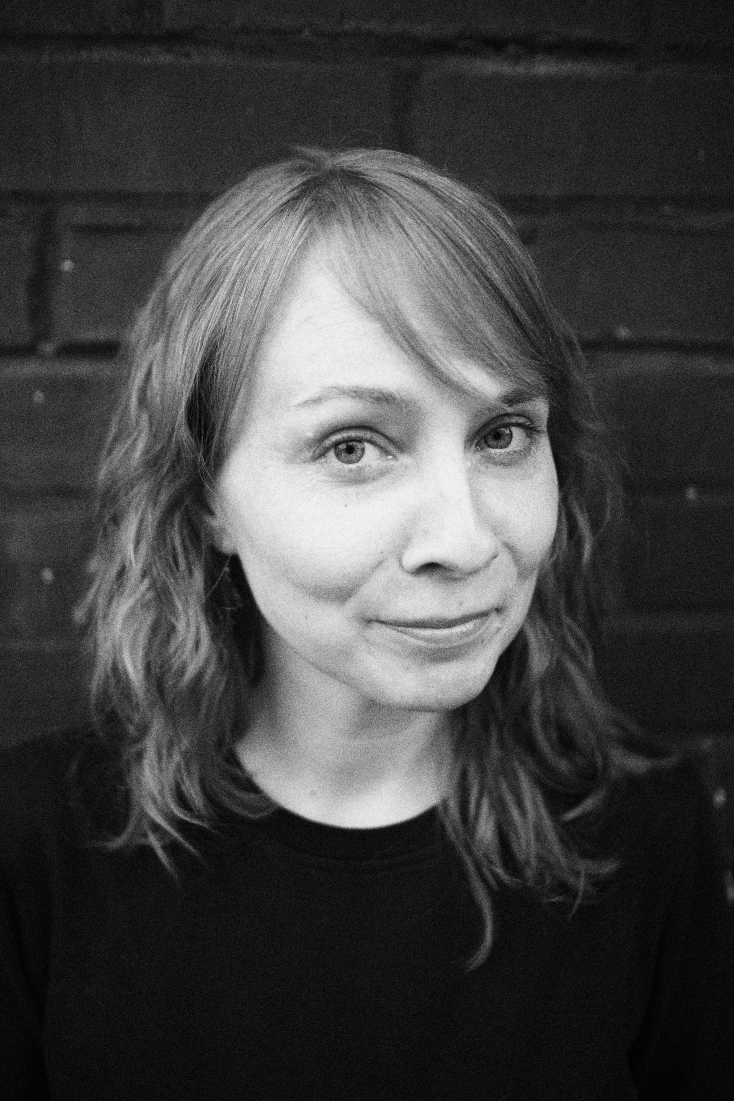 Женский близкий портрет на фоне темной киричной стены