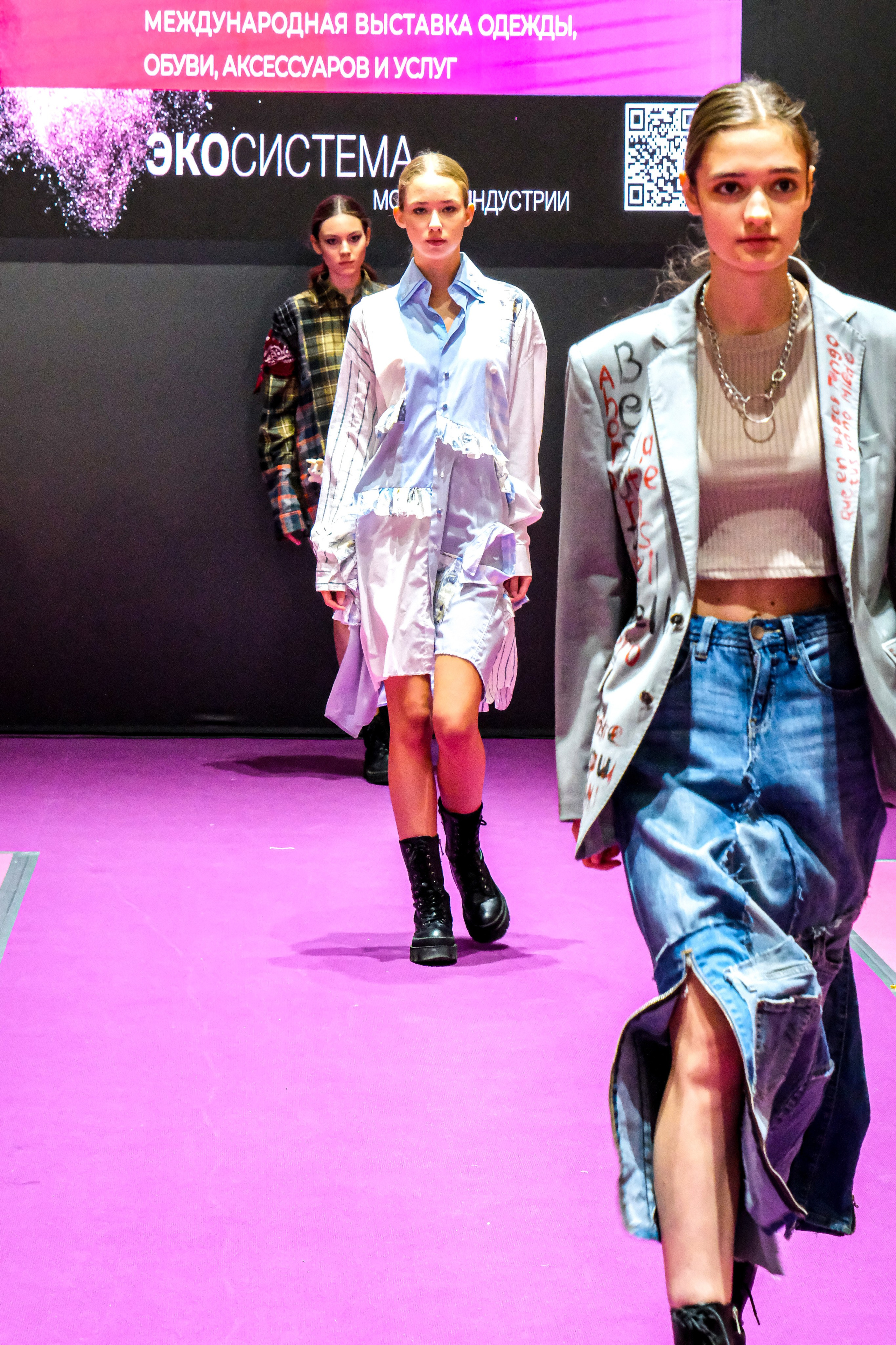  "Модели в ярких нарядах проходят по подиуму во время показа мод, освещенные яркими софитами и окруженные восторженными зрителями."