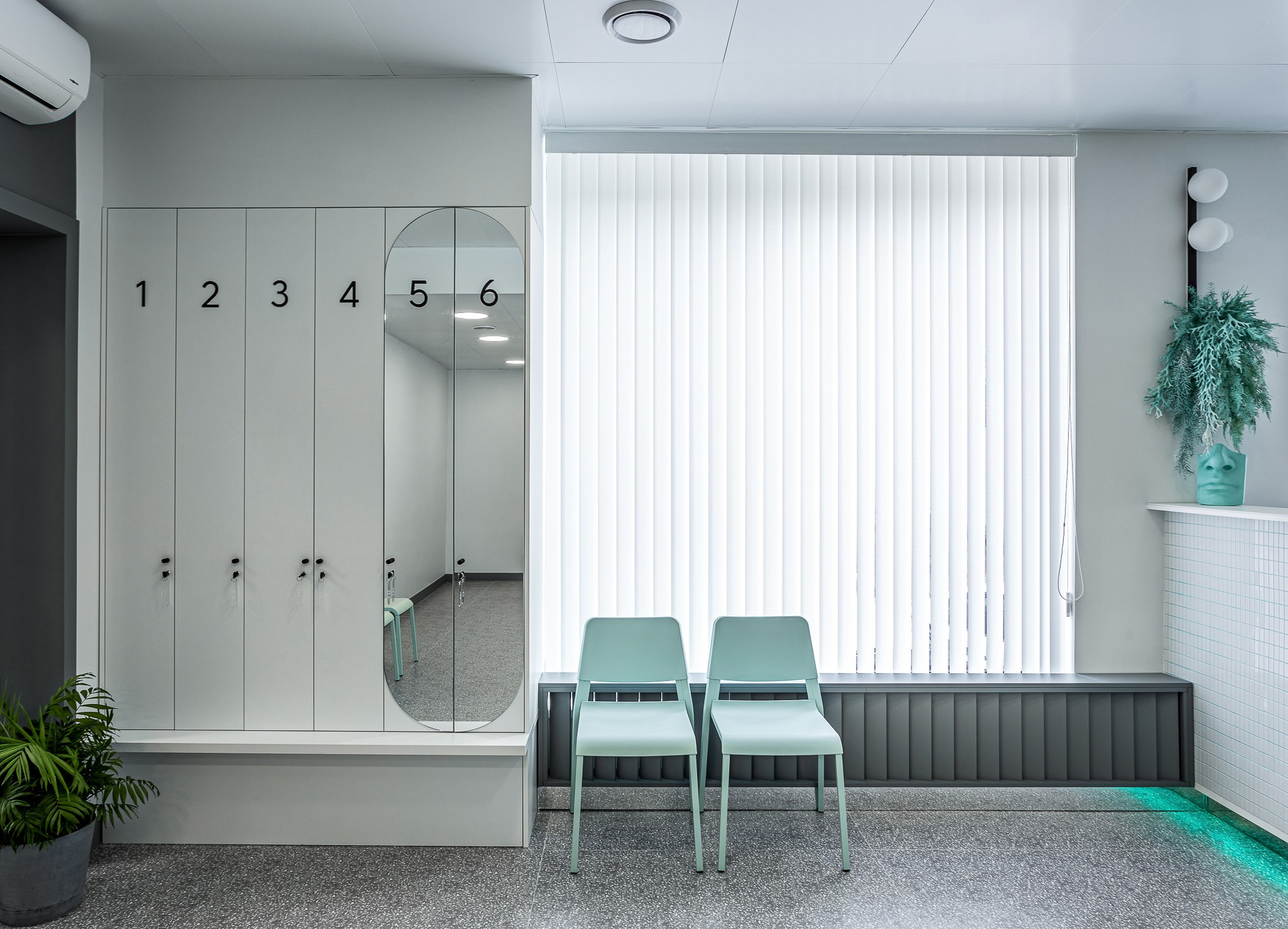 Серые шкафчики гардероба рядом со стульями мятного цвета.