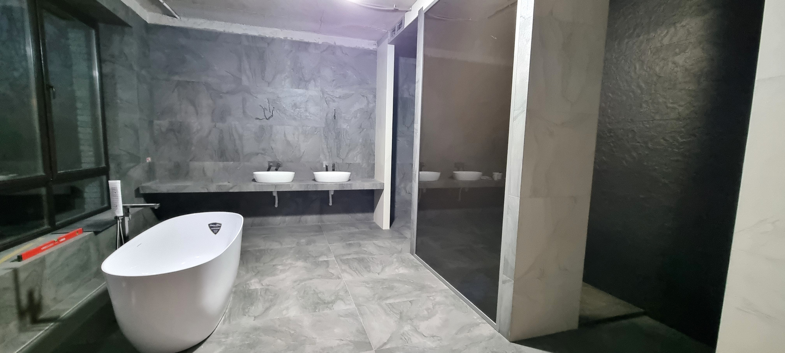 Свободностоящая ванна установлена на фоне стены из плитки под камень