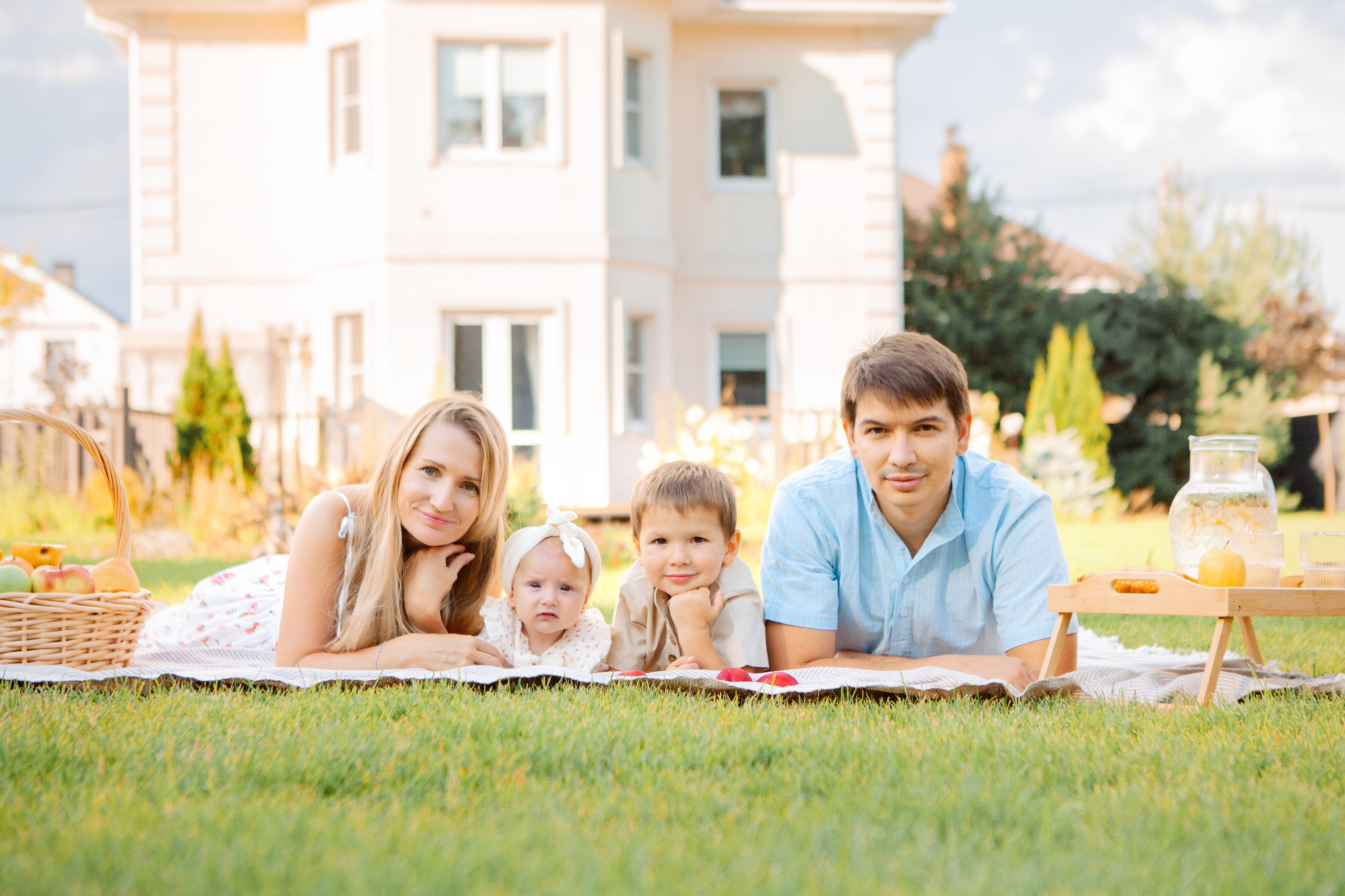 муж и жена на участке своего дома позируют  и улыбаются с сыном и дочкой.