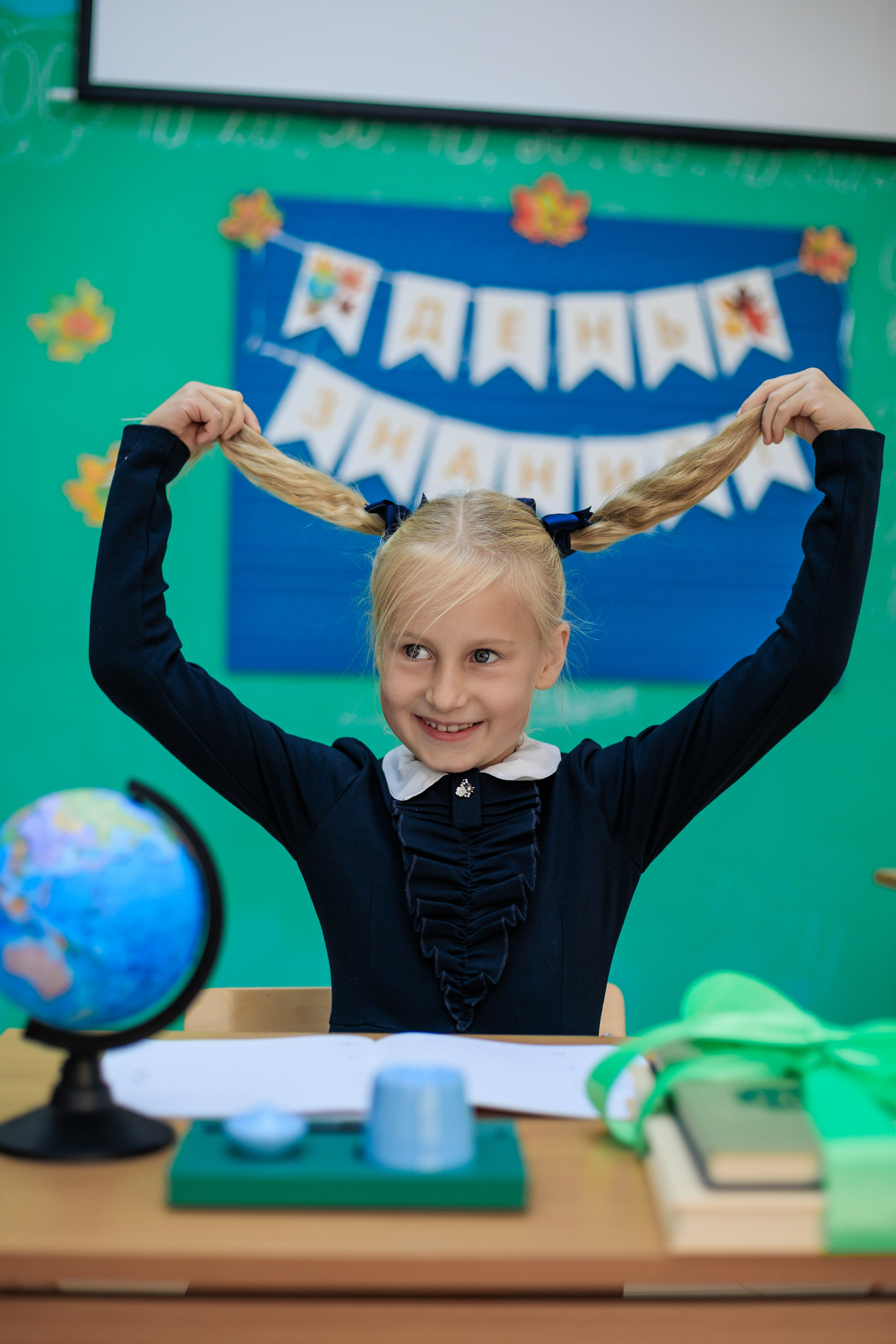 ученица тянет свои косички в разные сторы за партой