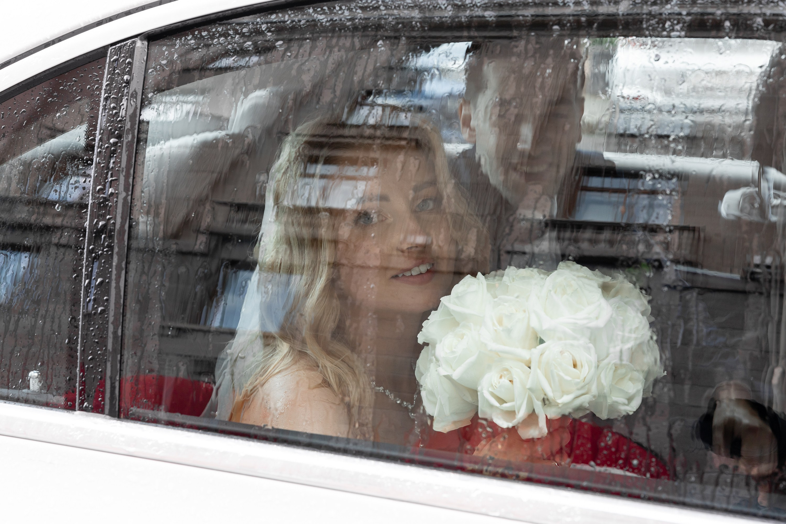 Жених и невеста прячутся от дождя в машине