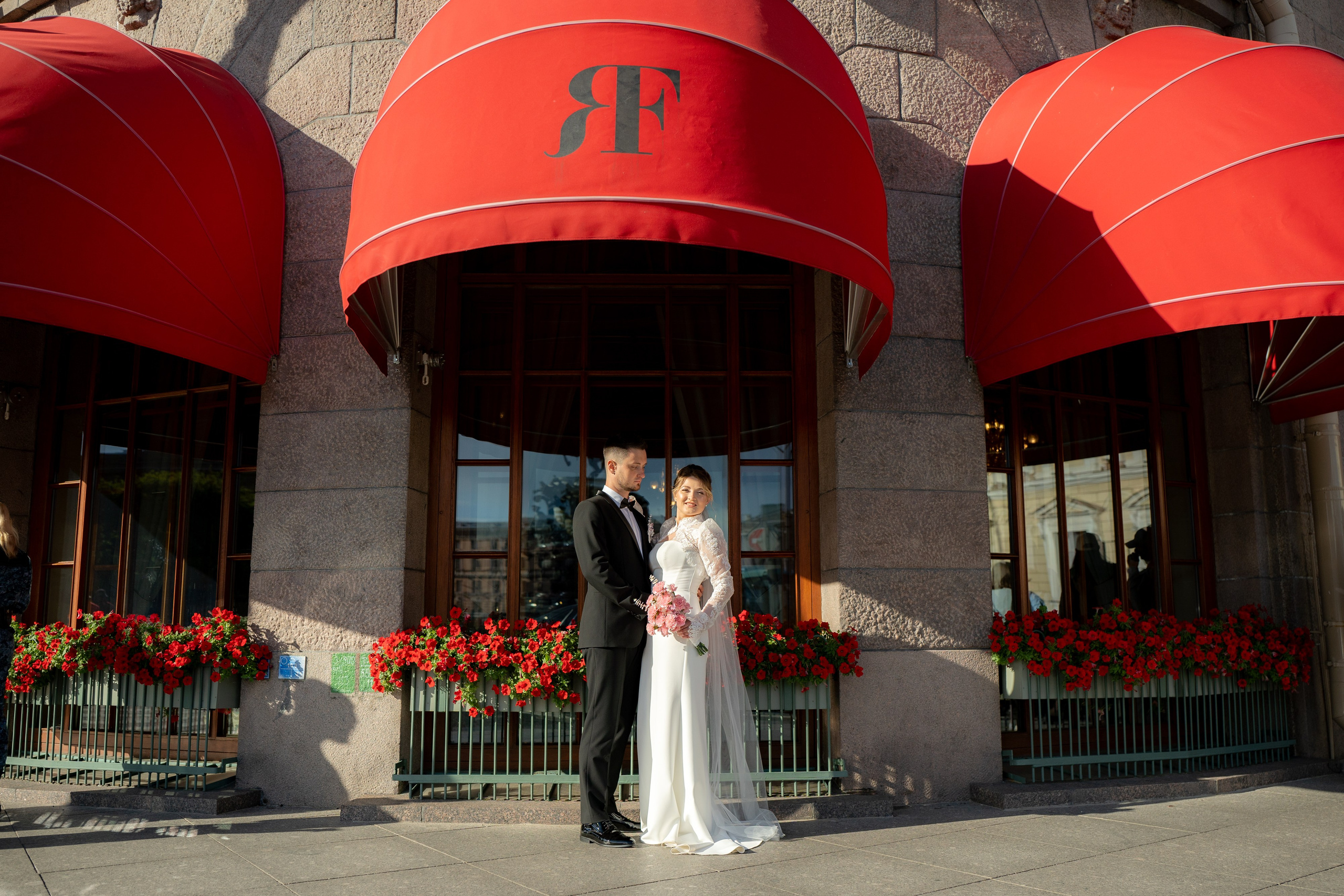 жених и невеста обнимаются под красными зонтами маркизами гостиницы Астория. Свадебная фотосессия у Астории в Санкт-Петербурге.