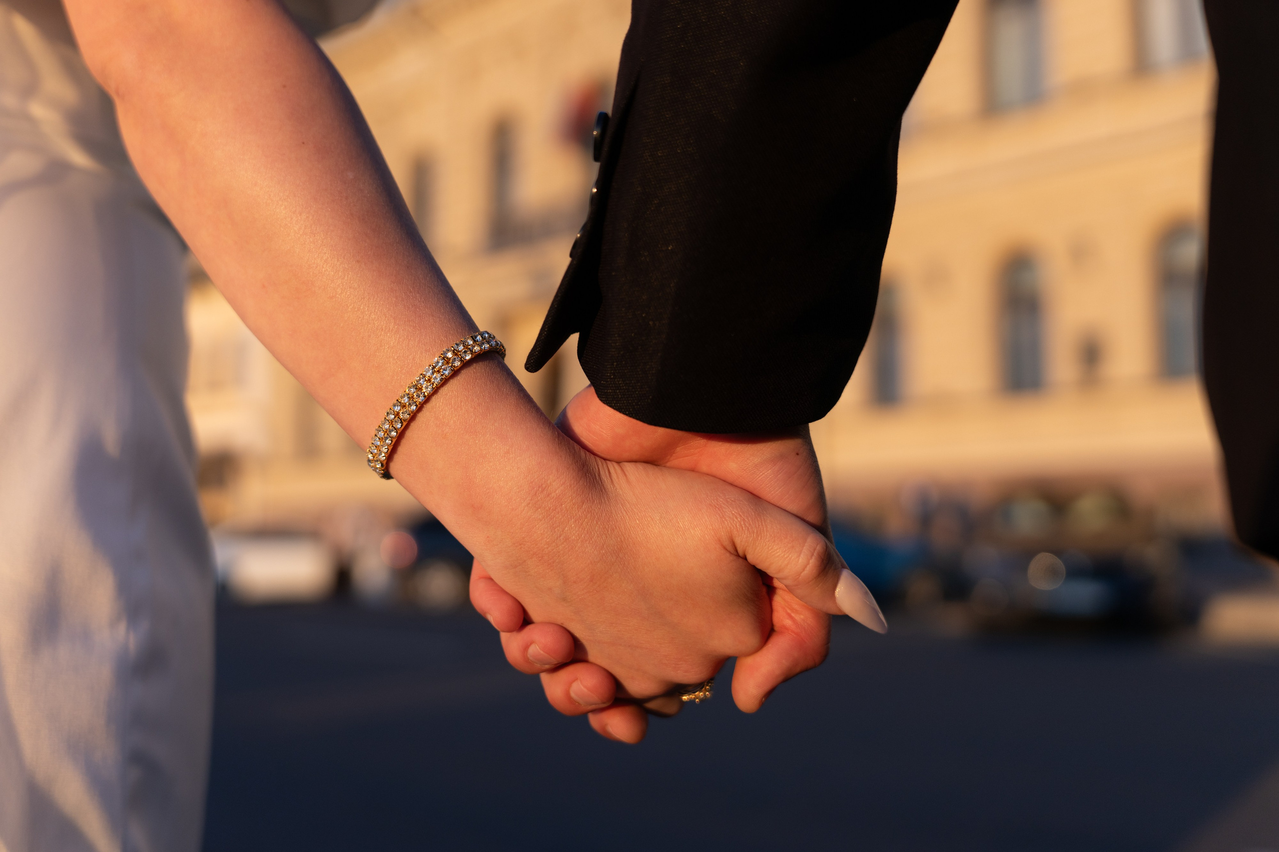 жених и невеста держат друг друга за руки на закате