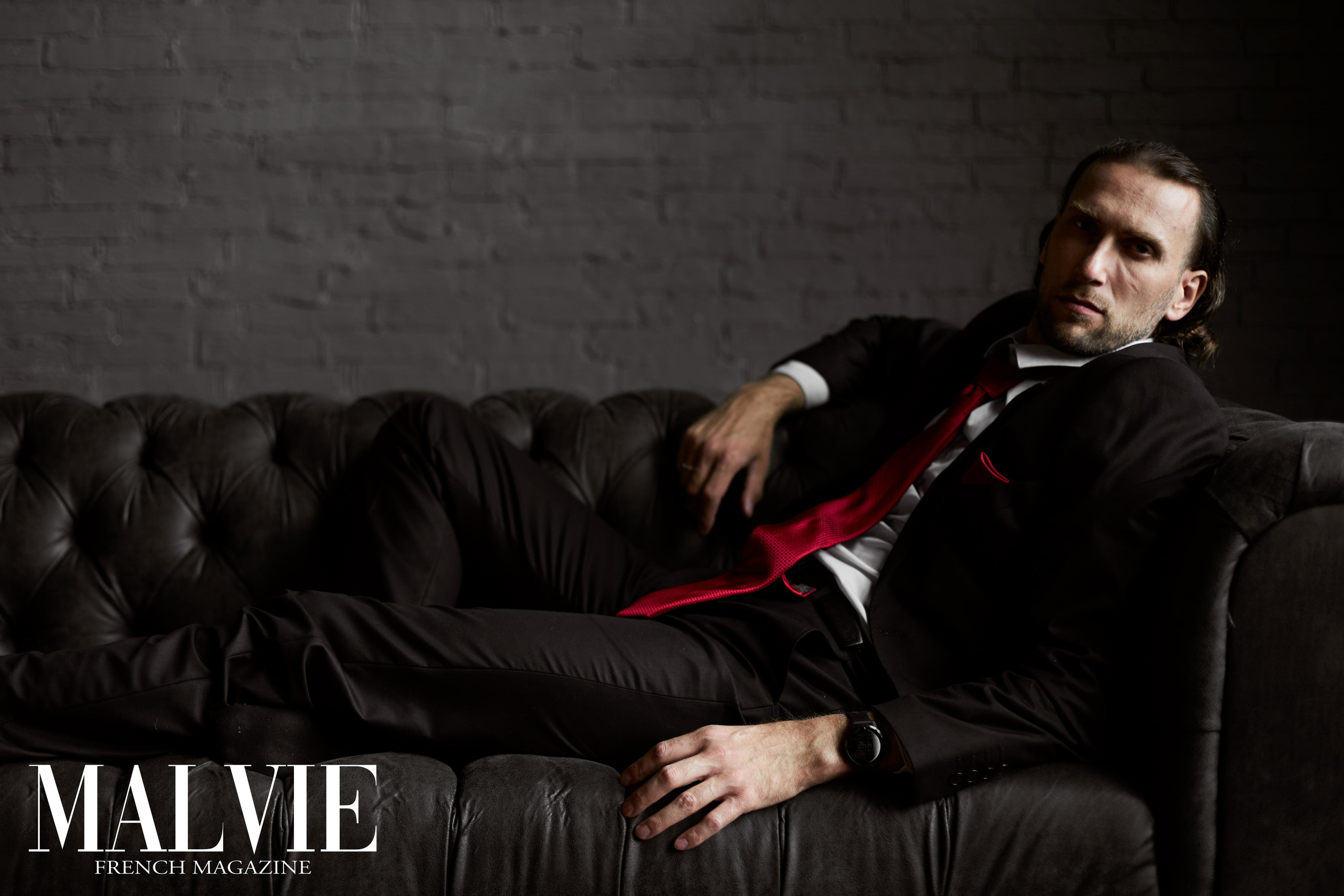 Портрет мужчины в костюме, лежащего на кожаном диване