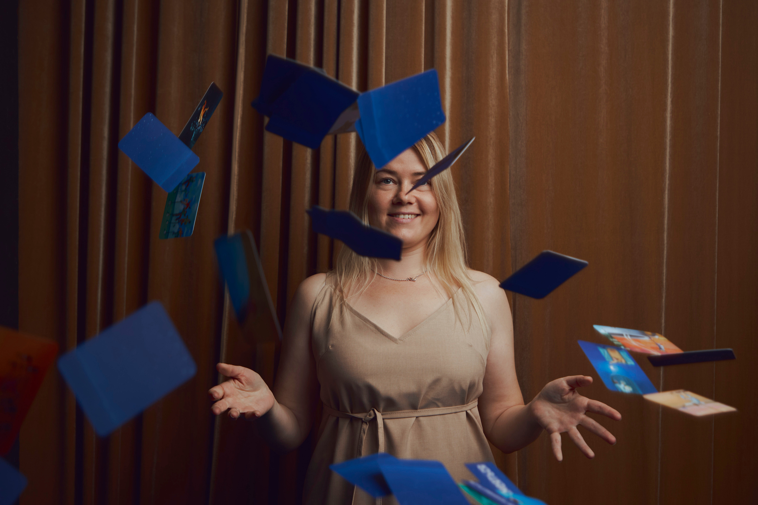 Девушка подкидывает вверх карты Таро и они как будто летают вокруг неё