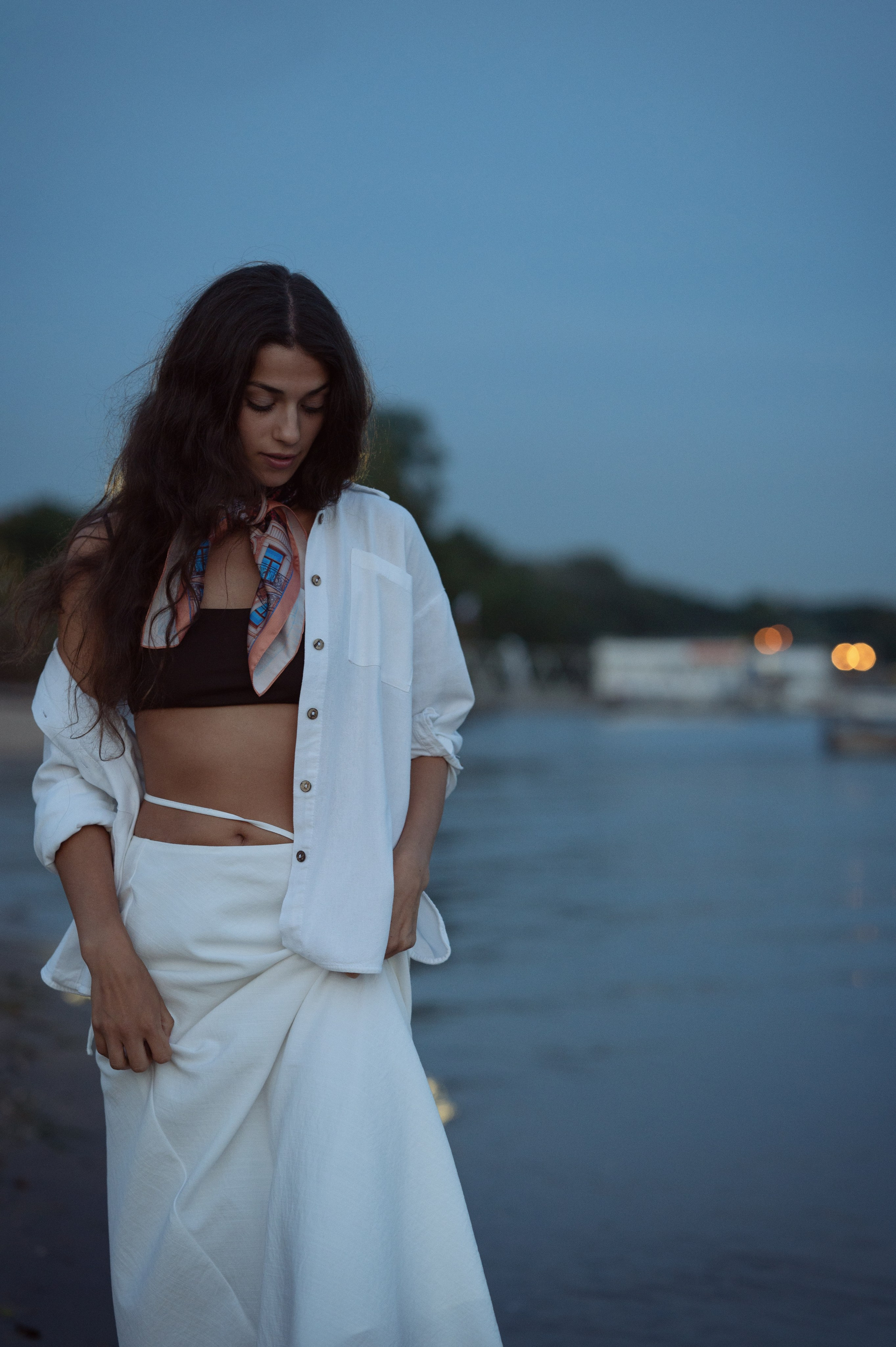 Красивая длинноволосая брюнетка в светлой одежде на фоне водной глади