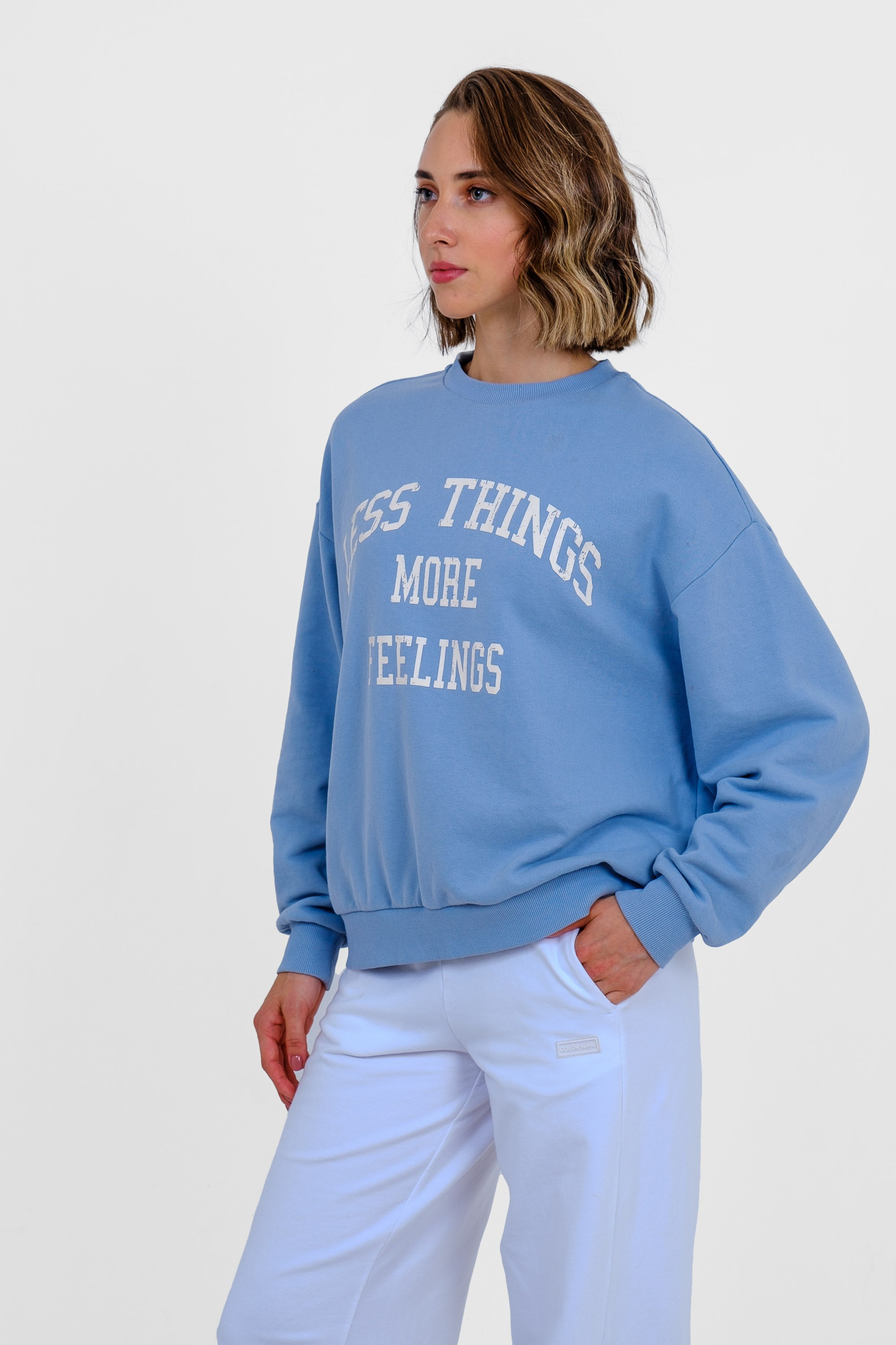 Девушка с длинными волосами в голубом свитшоте с принтом и голубых спортивных брюках. Фото для маркетплейсов