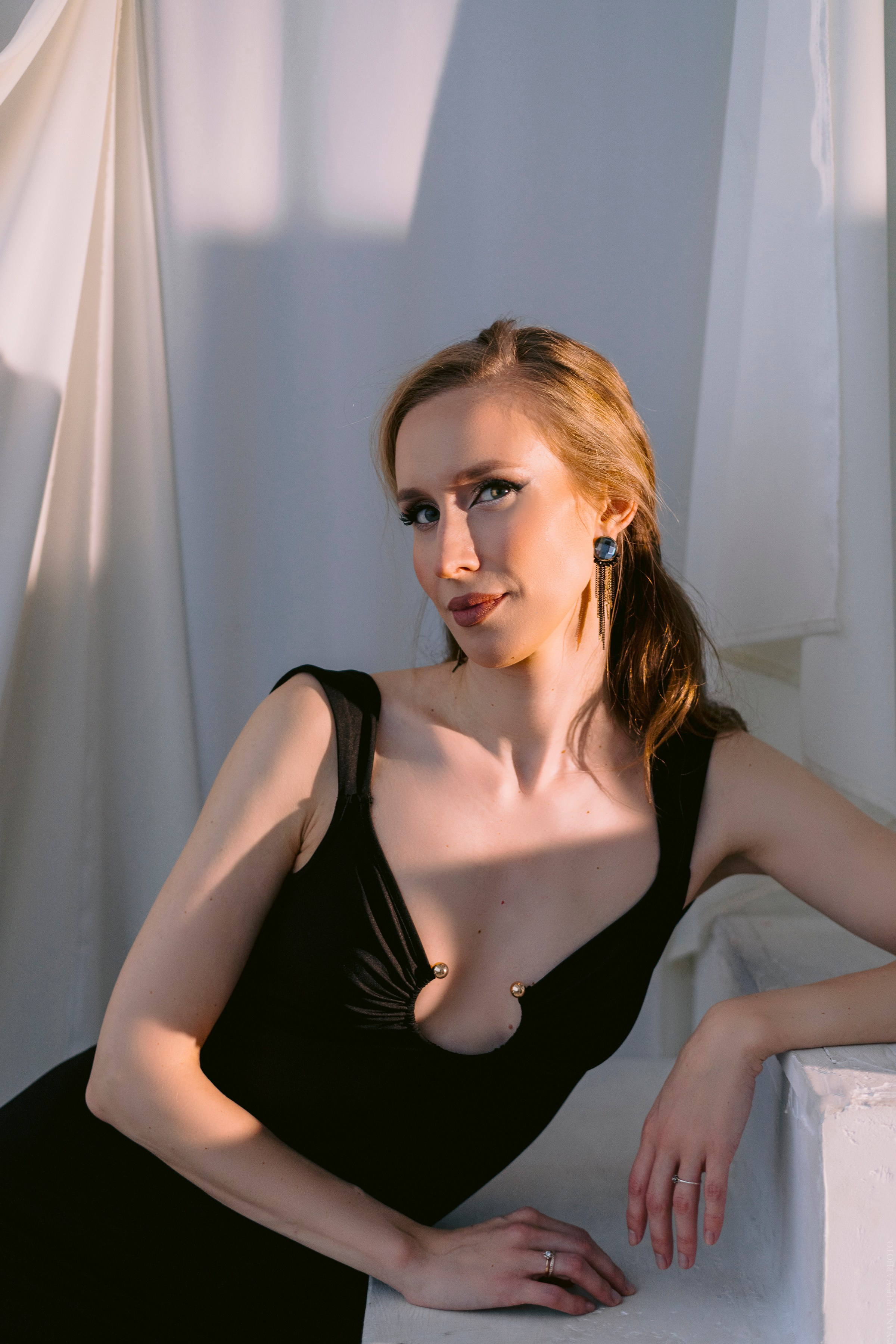 девушка в черном длинном платье с вырезом на белом фоне