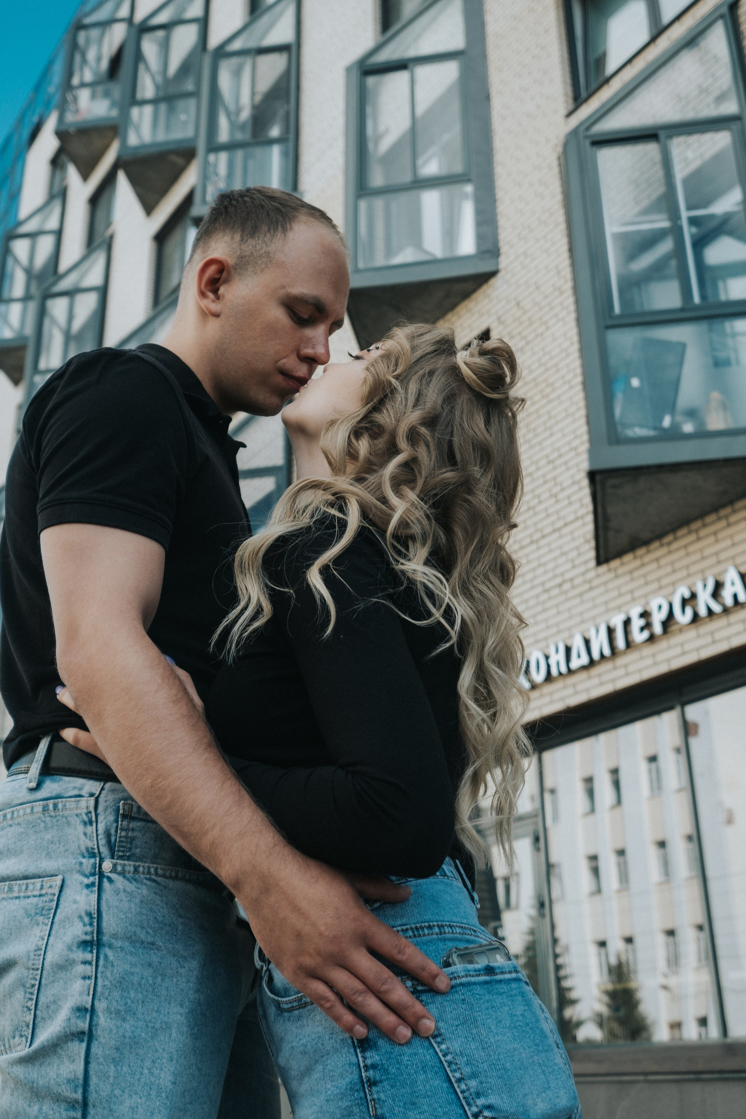 Молодая пара мужчина и девушка дурачатся в городских локациях в черных футболках и синих джинсах, лав стори для влюбленной пары на кануне свадьбы