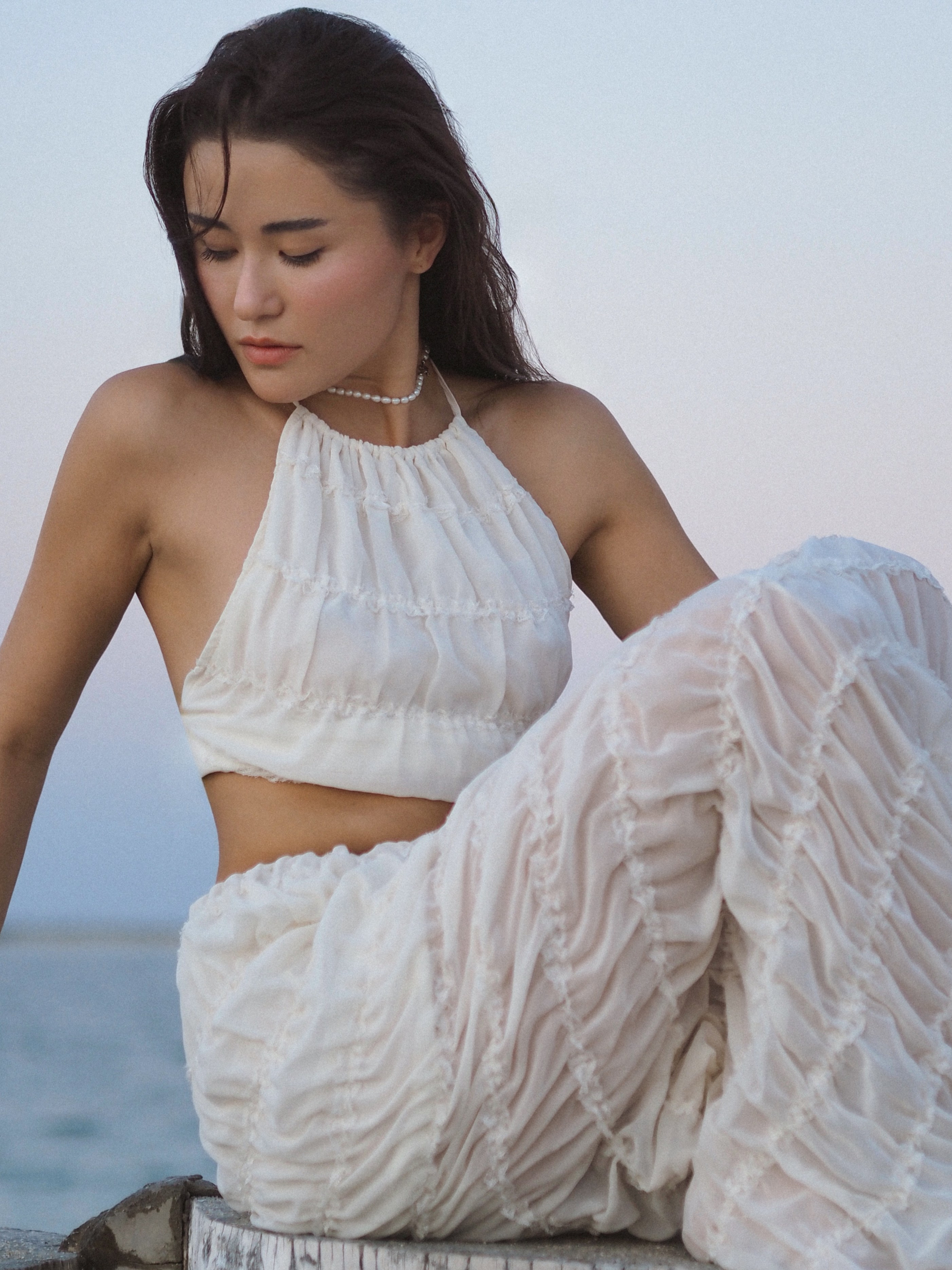 Летняя фотосессия на пляже — девушка в белом наряде.
