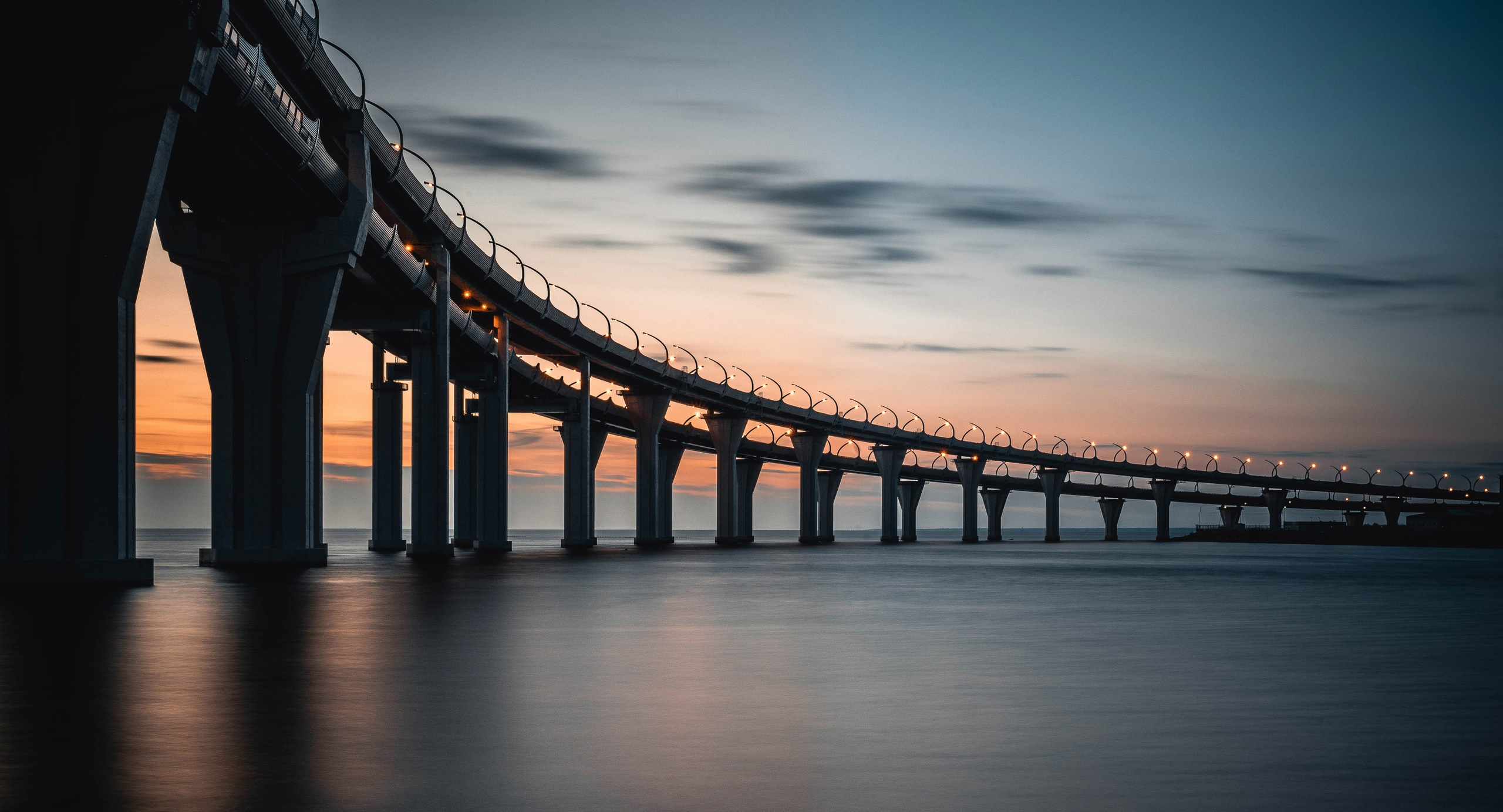 Канонерский остов. Вантовый. Мост ЗСД  через Финский залив  в Санкт-Петербурге на закате, голубые сумерки и отражения в воде, пейзажная фотография города.