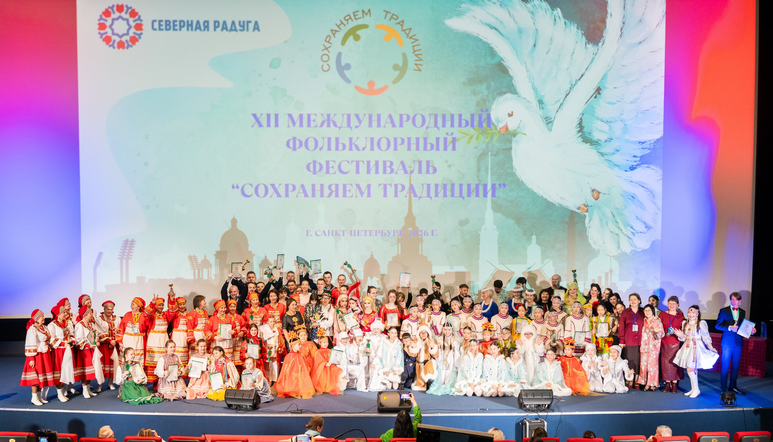 Финальное групповое фото всех участников, детей и взрослых на XII Международном фольклорном фестивале «Сохраняем традиции». Санкт-Петербург, 2026. Фотограф: Евгений Мальцев.