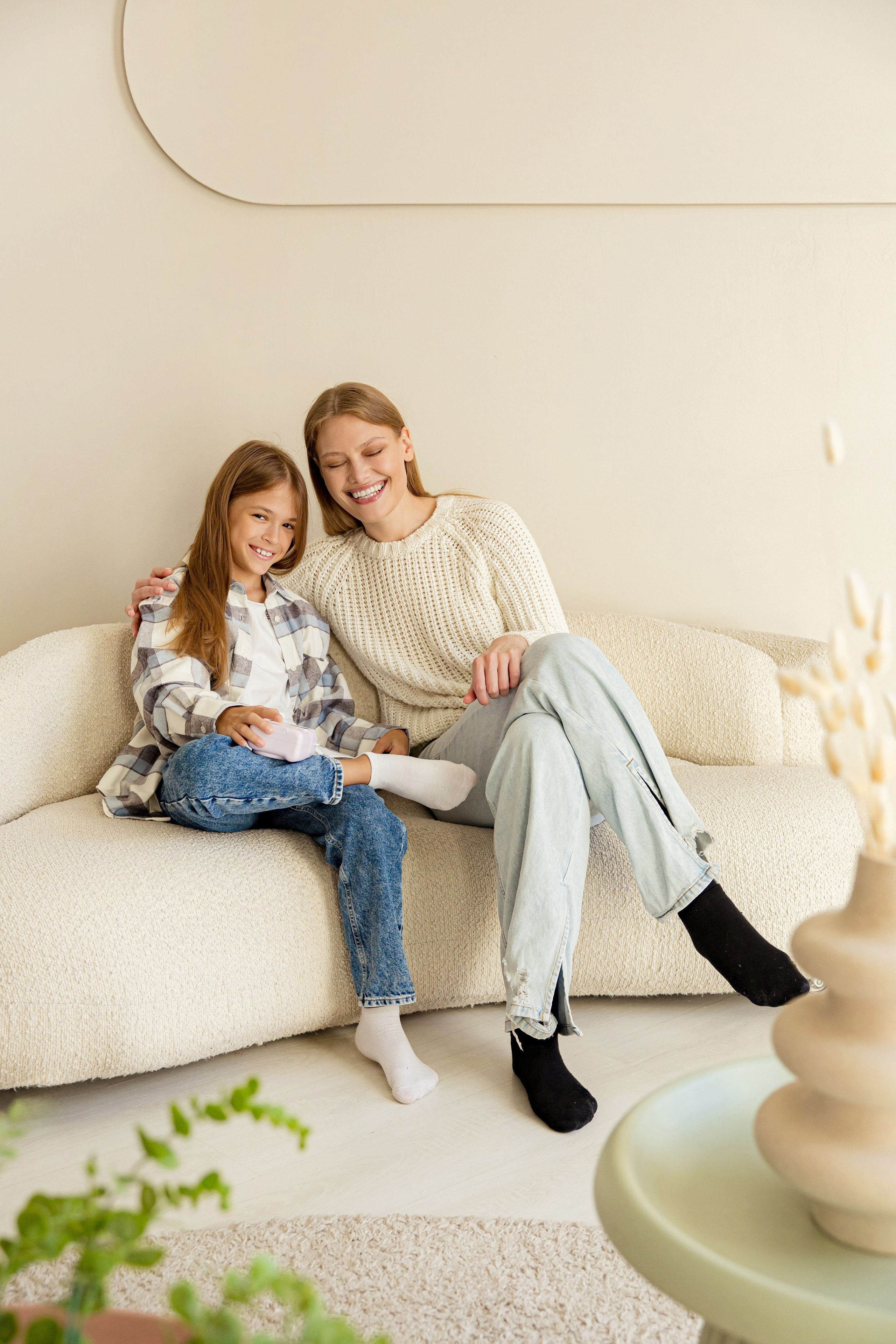 Сестры сидят на диване и смотрят на фотоаппарат моментальной печати