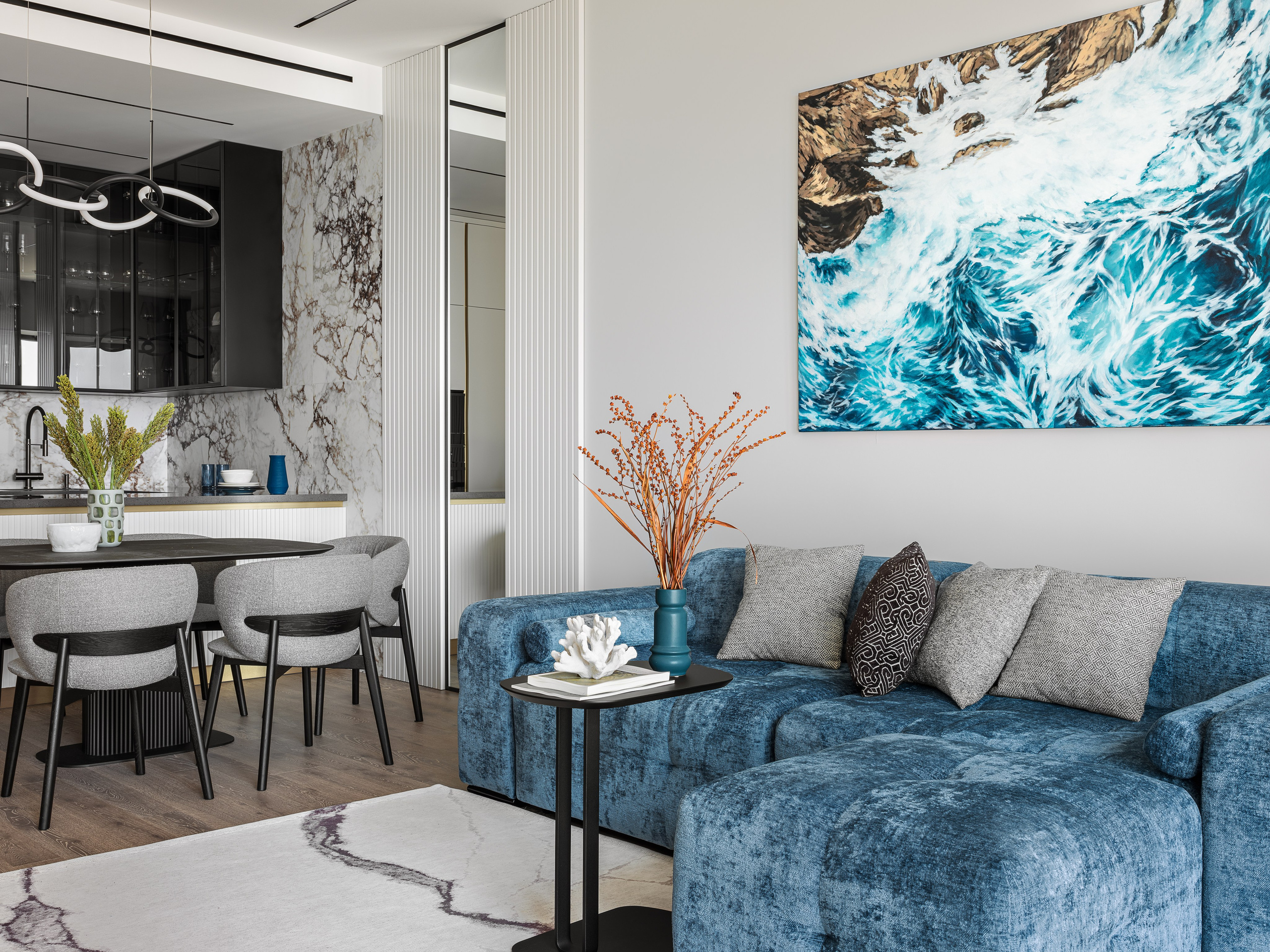 Современный интерьер кухни-гостиной с мраморными стенами, черными фасадами и мягким освещением; гармония текстур и оттенков создана дизайнерами Ренатом Байчуковым и Алесей Кириенко, стилист Екатерина Ракитина, фотограф Сергей Денисенко.