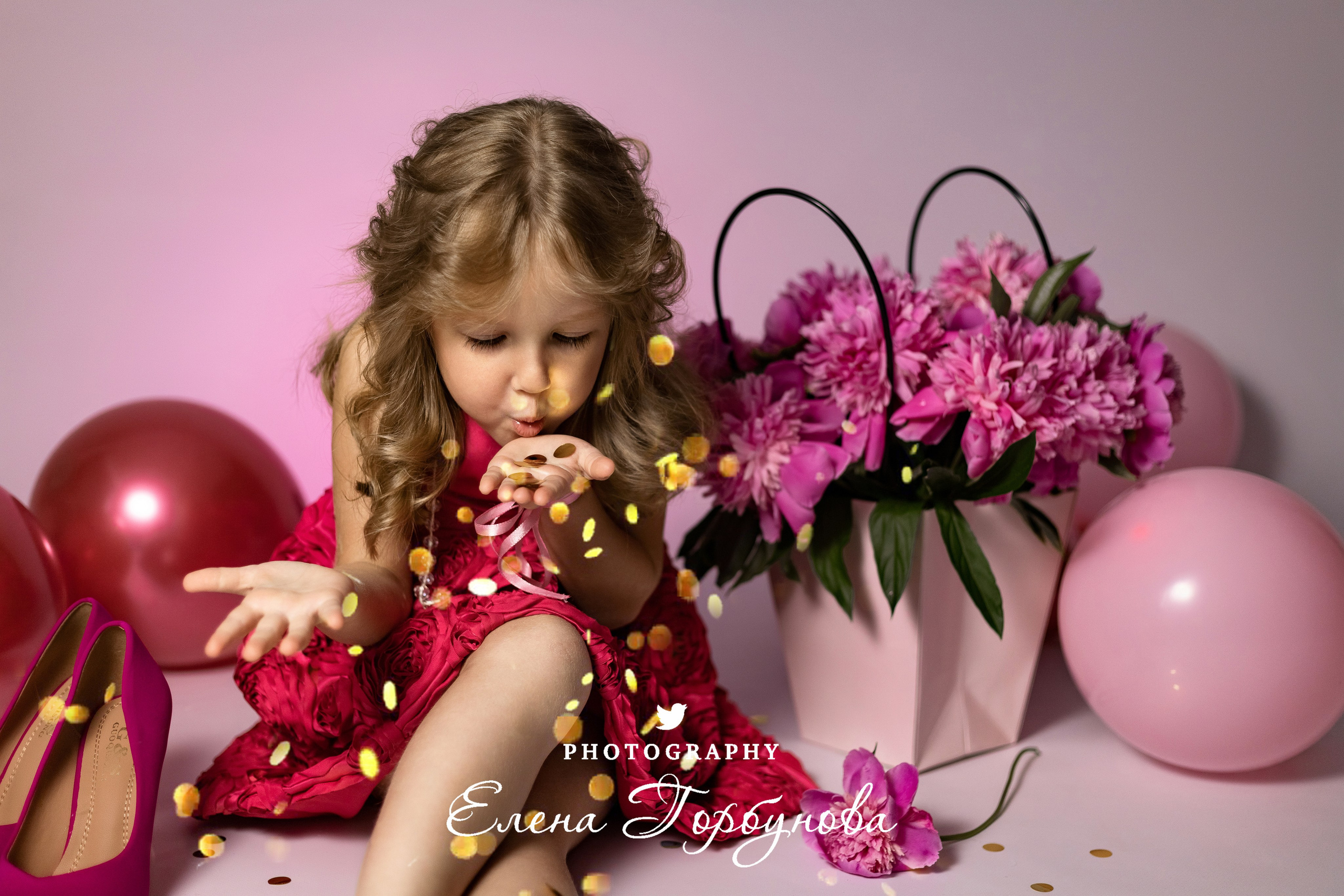 девочка модница в розовом с пионами раздувает блестки на фотосессии в студии