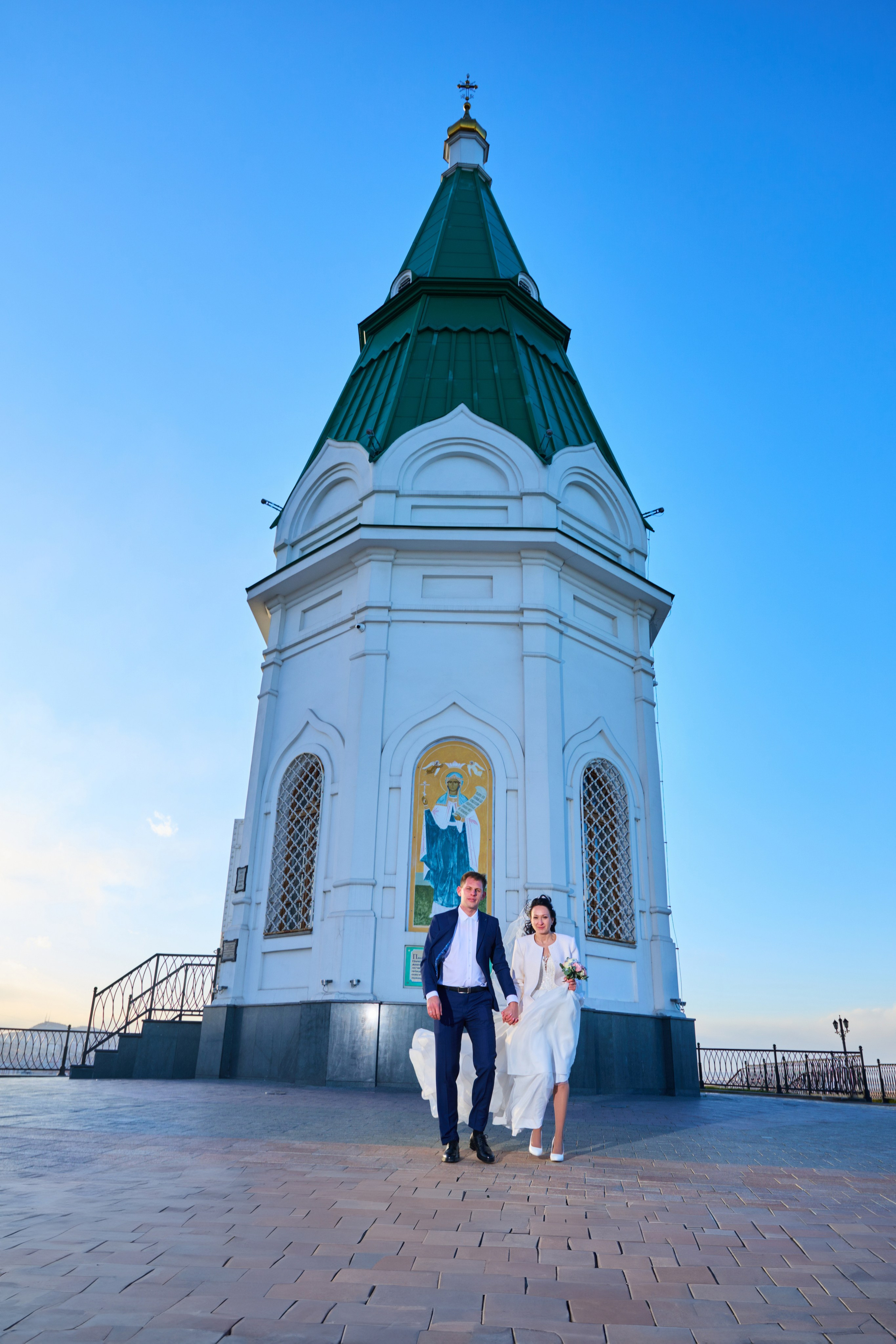 жених за руки ведет невесту от часовни