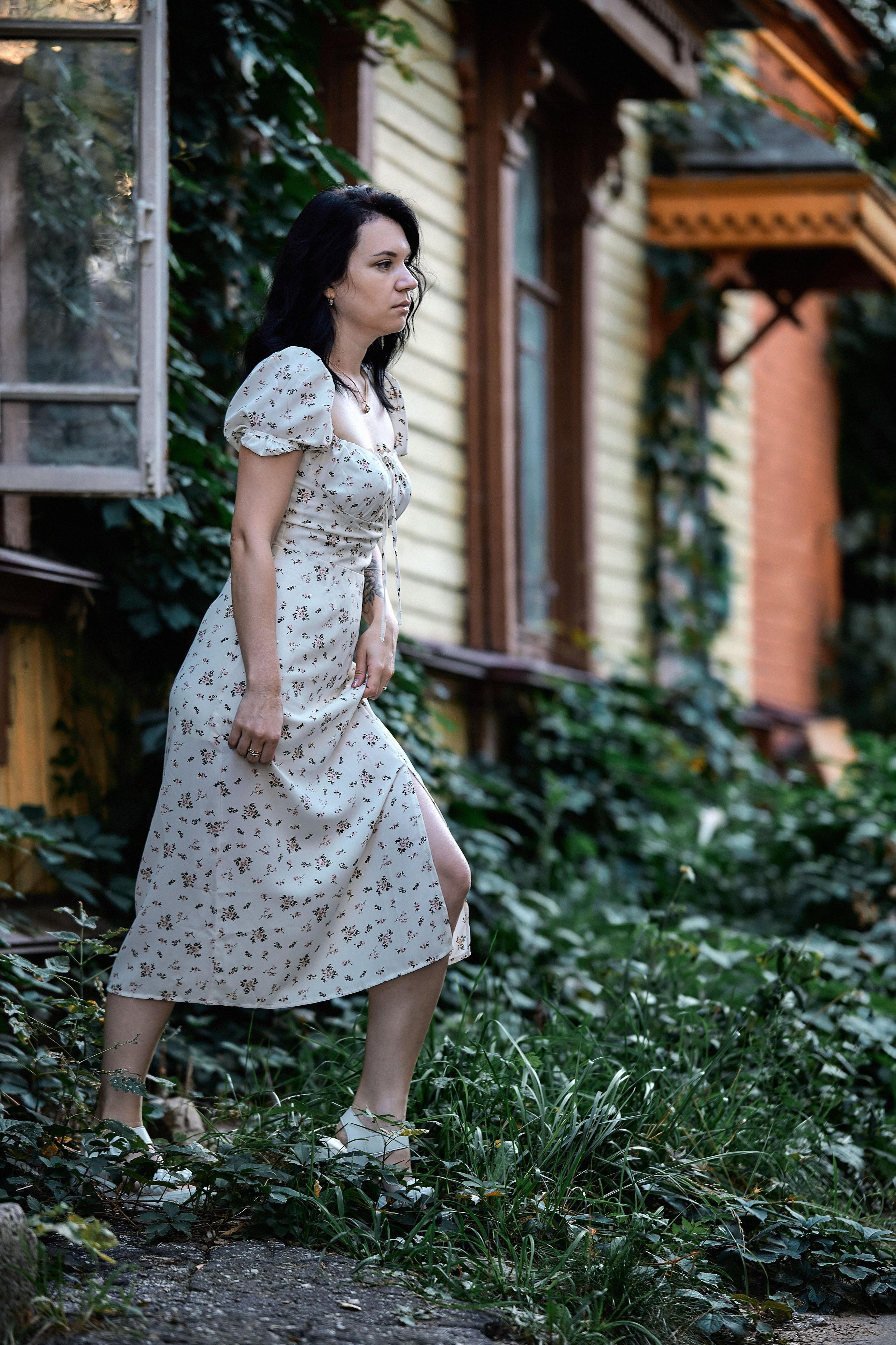 Стильный образ в светлом платье с романтическими нотками на фоне старинного здания