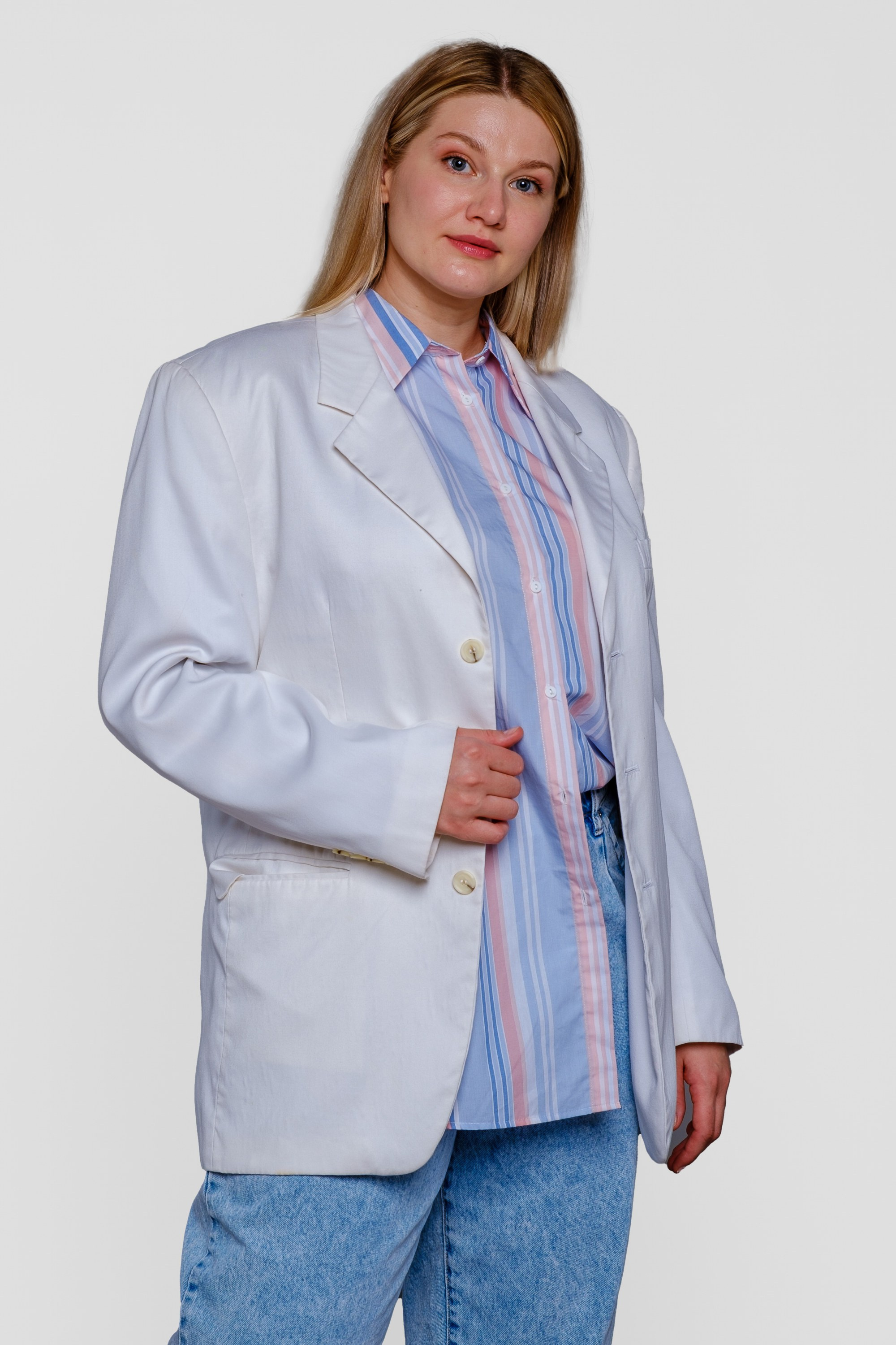 Девушка оверсайз в белом пиджаке и голубых брюках показывает модель. Вид спереди. Фото для маркетплейсов