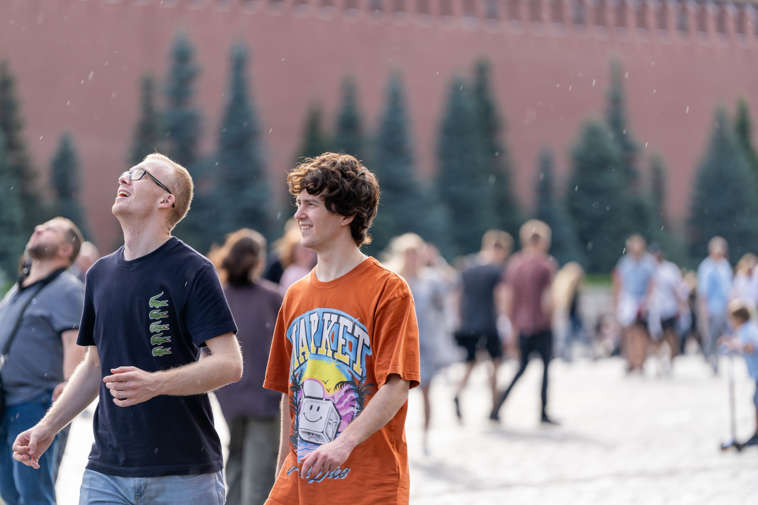 Молодые люди радуются летнему дождю на Красной Площади в Москве