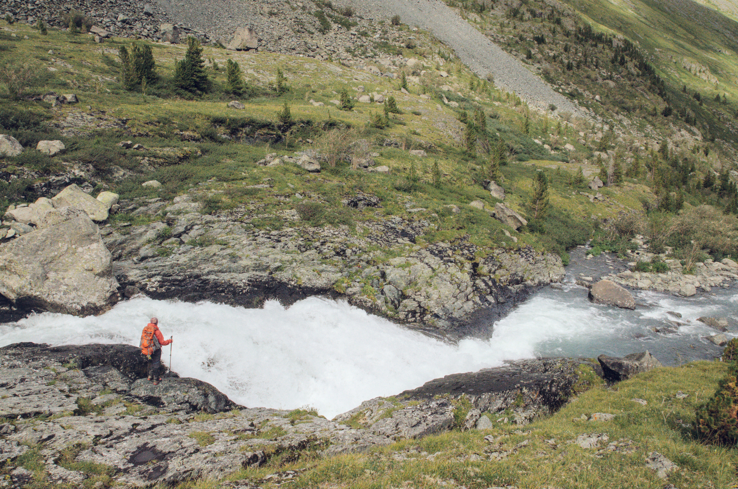 Человек смотрит на водопад в каньоне на Алтае