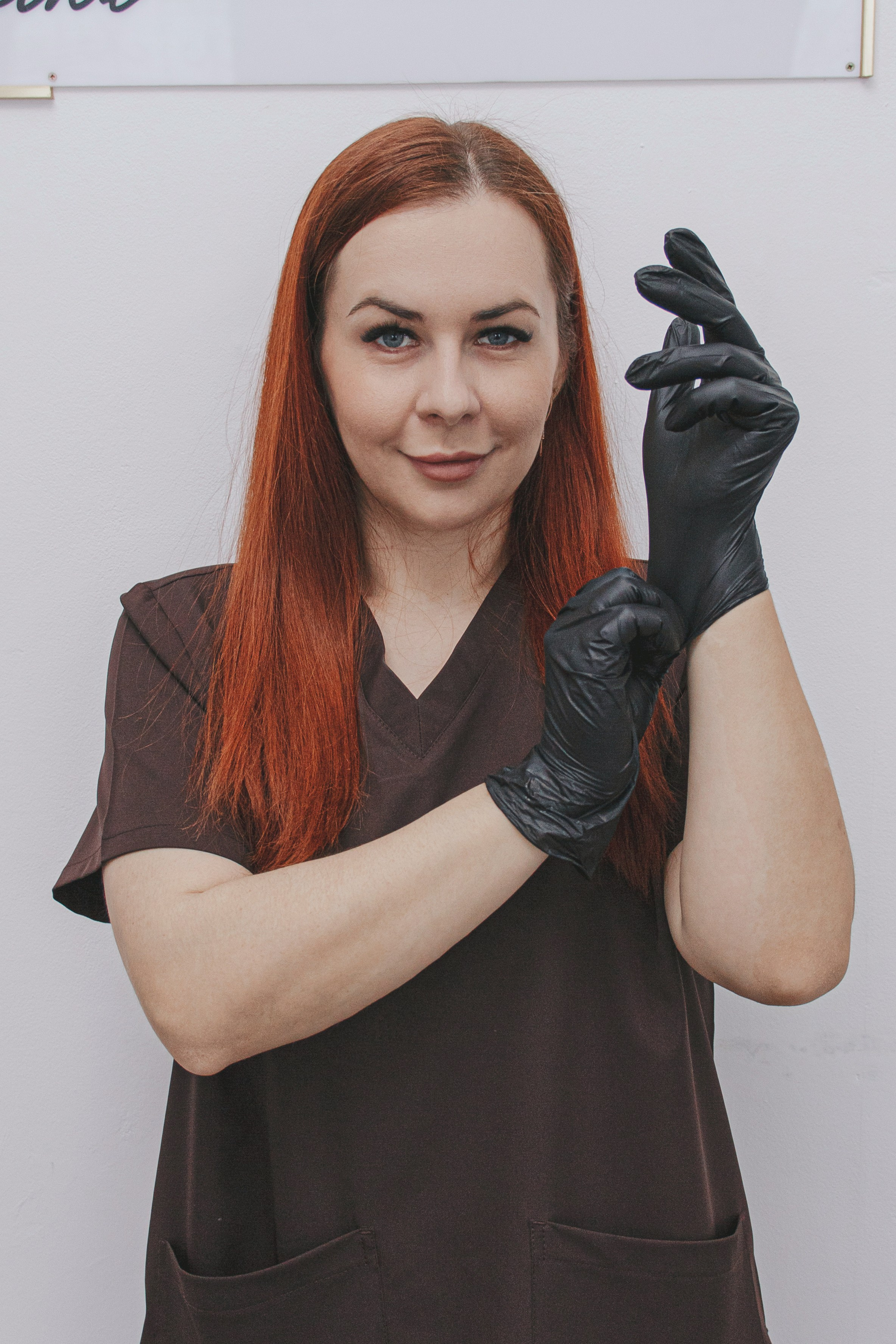 Косметолог готовитсся к процедурам, в костюме и перчатках