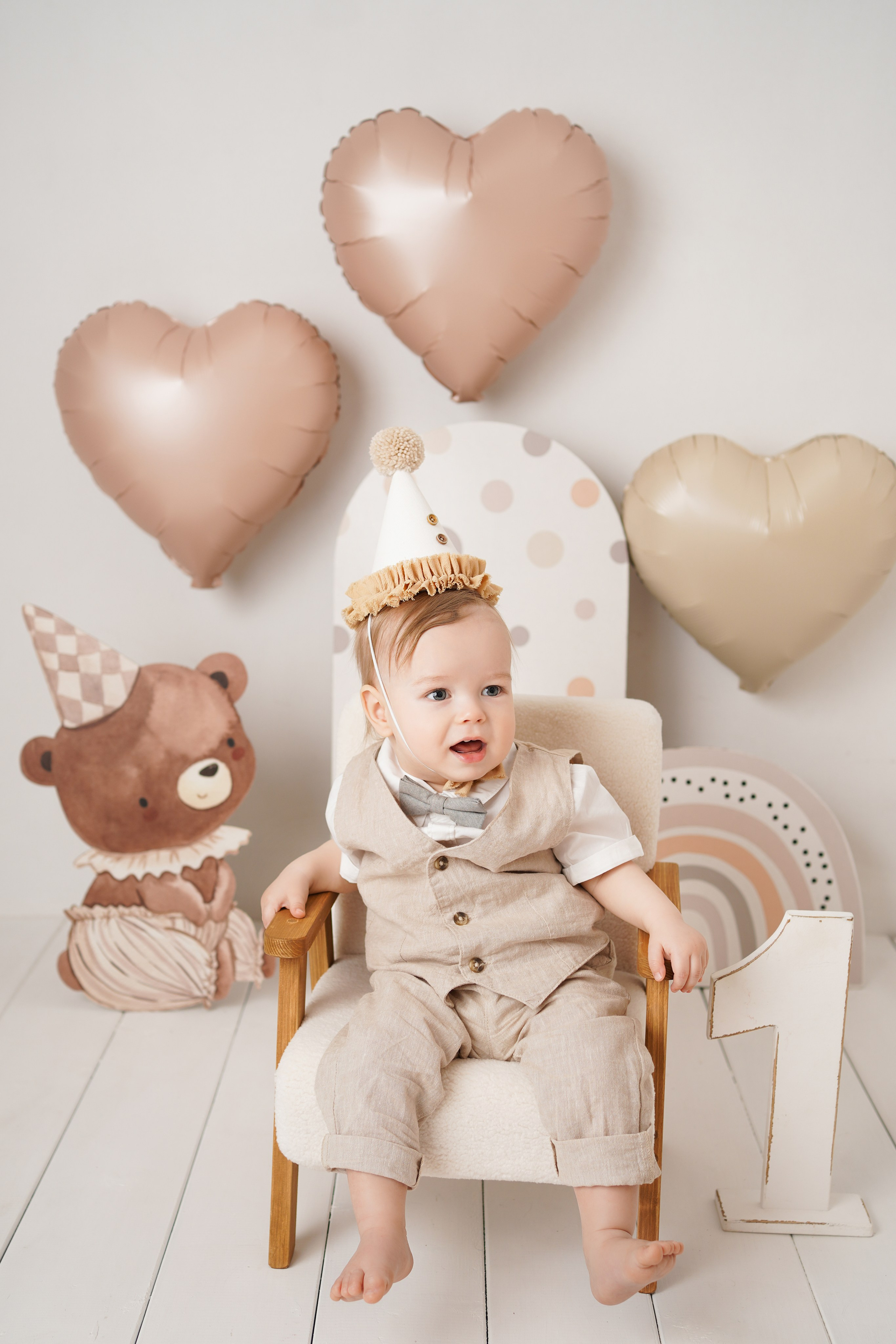 На фото малыш в нарядном костюме, рядом красивые шарики, единичка, тортик.