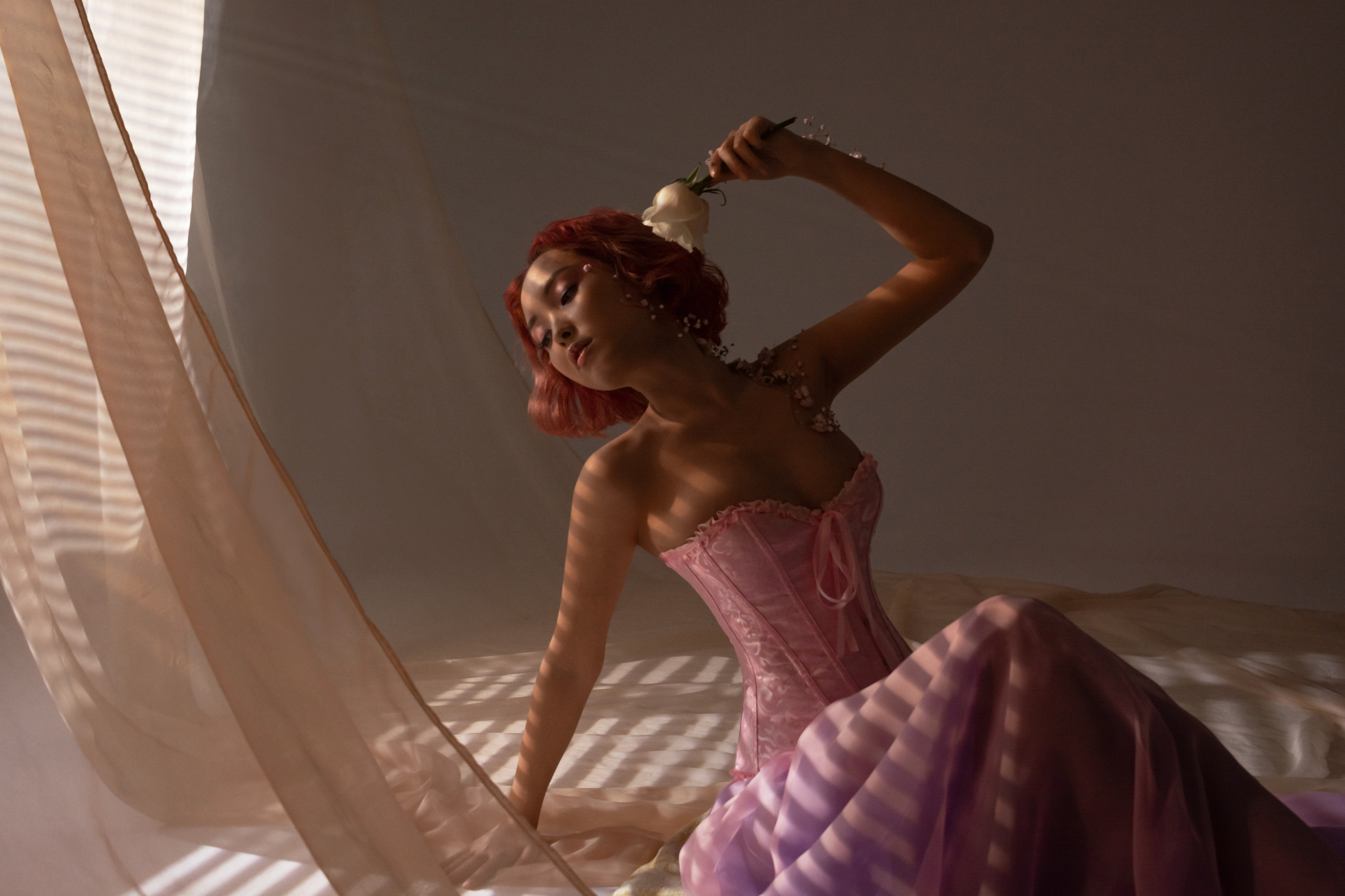 Утопая в лучах света, девушка в романтичном розовом платье с телом, украшенным цветочными узорами, воплощает саму идею пробуждения природы, знаменуя собой переход от зимы к цветущей весне.