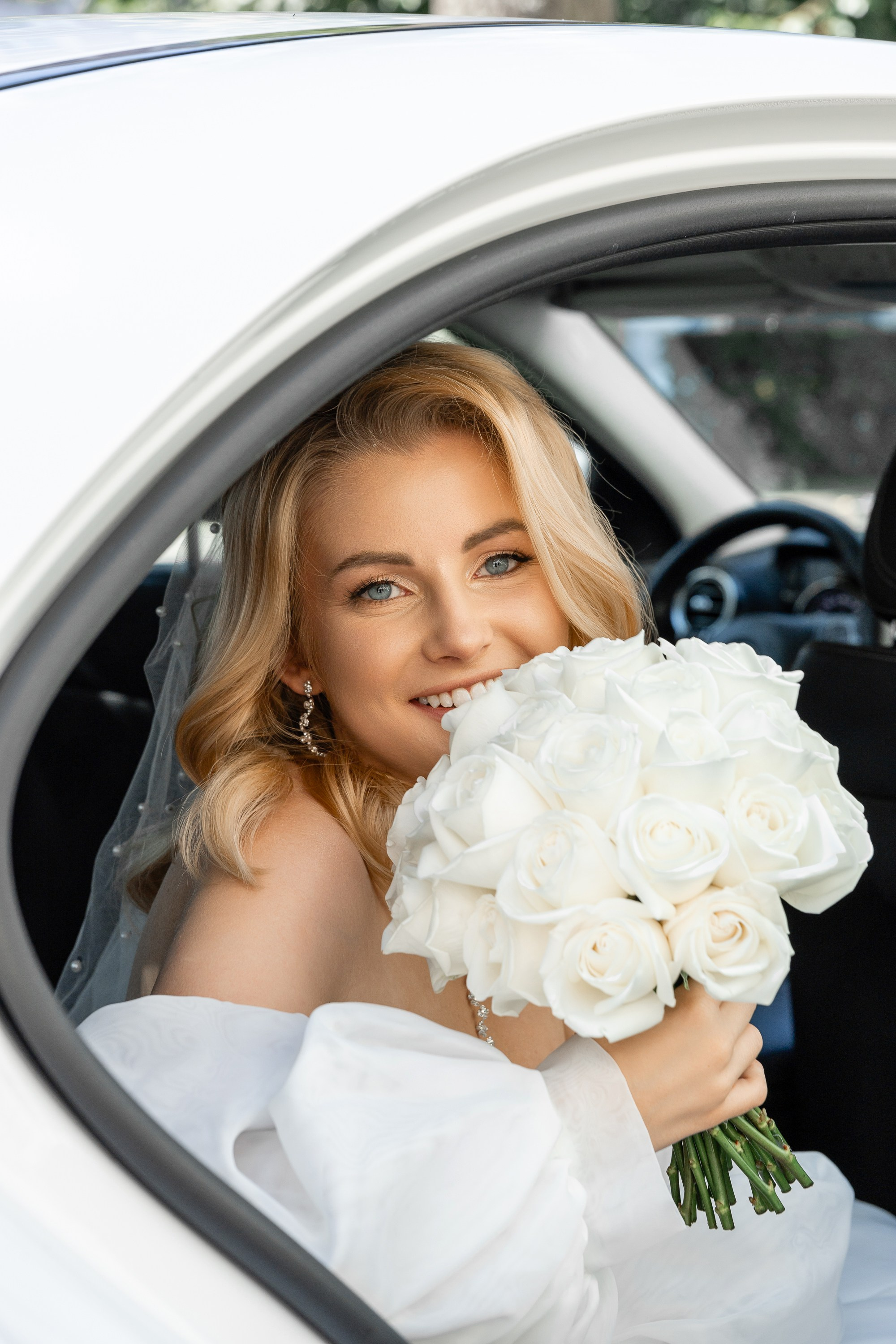 Невеста с букетом цветов в свадебной машине