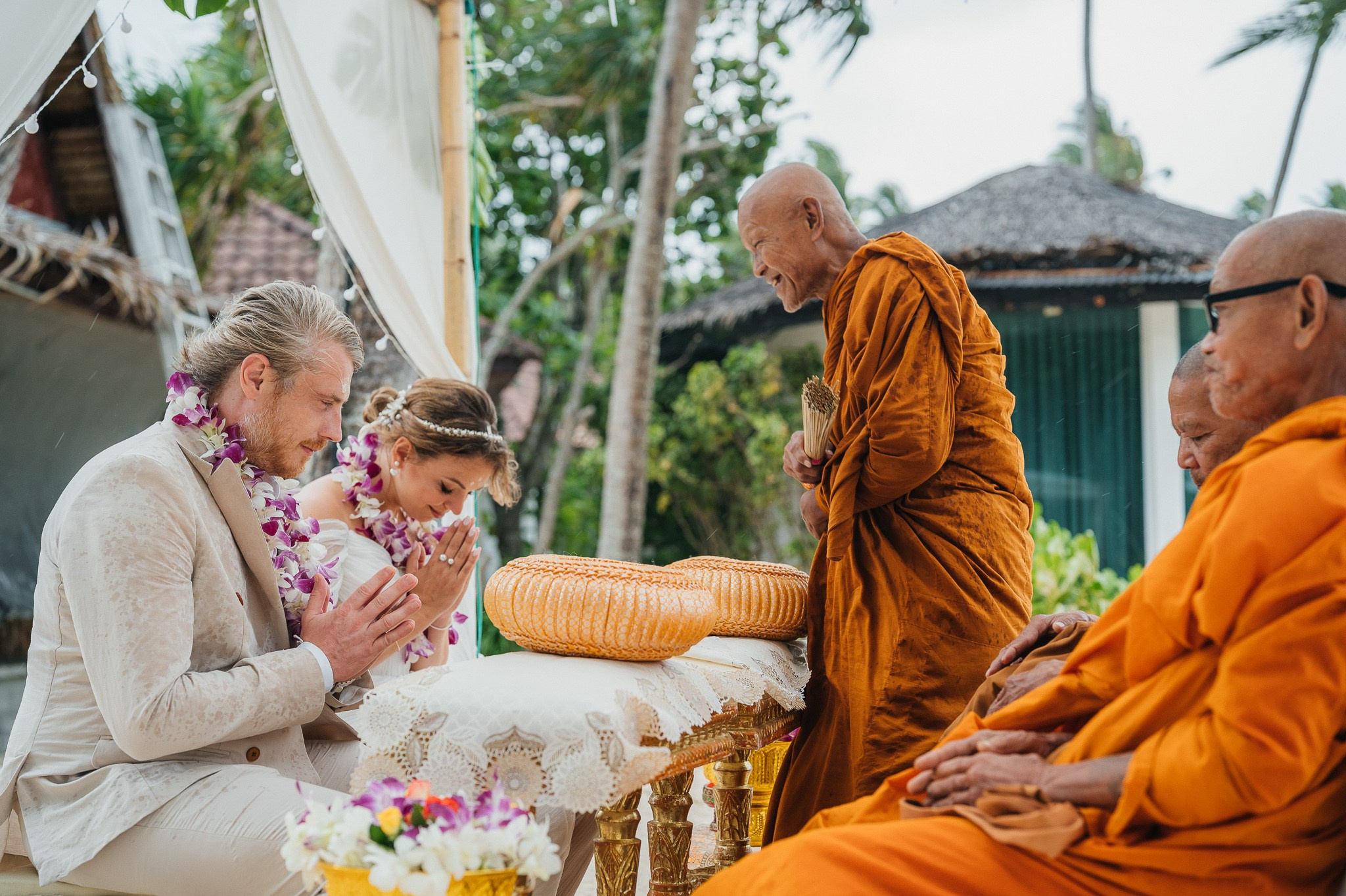 Bride and groom receiving blessings during a Buddhist wedding ceremony on the beach in Koh Samui, Thailand.