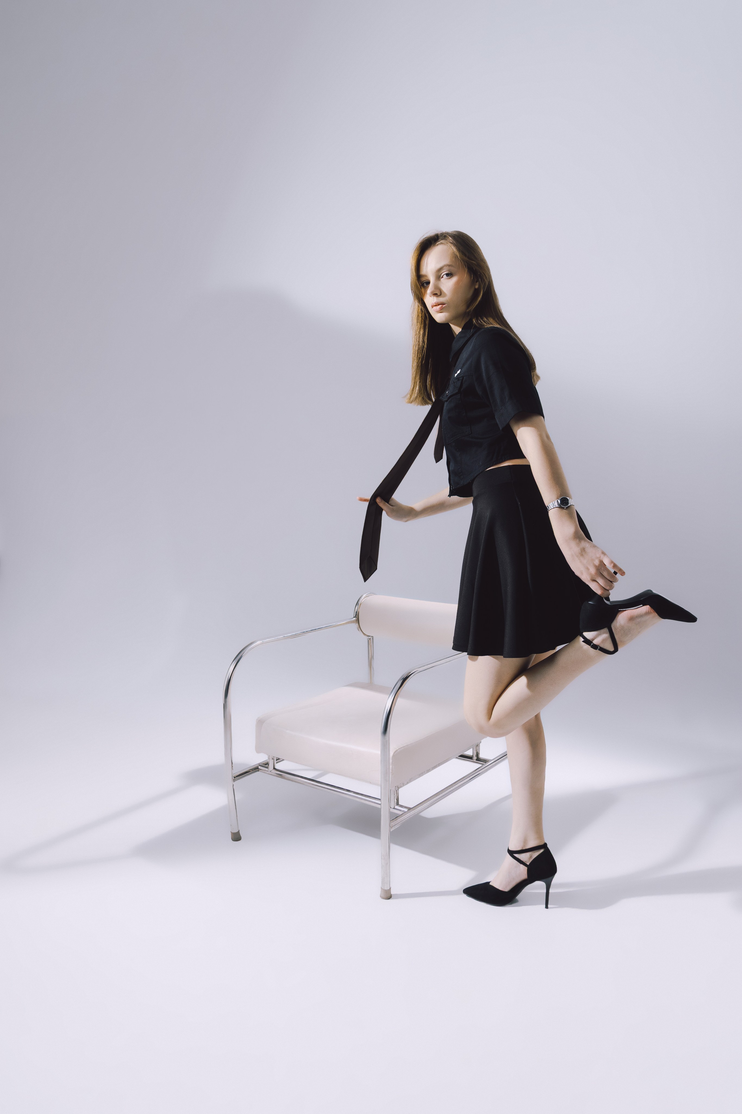 Белая студия, хромированное кресло и модель в деловом наряде — сочетание простоты и шика.