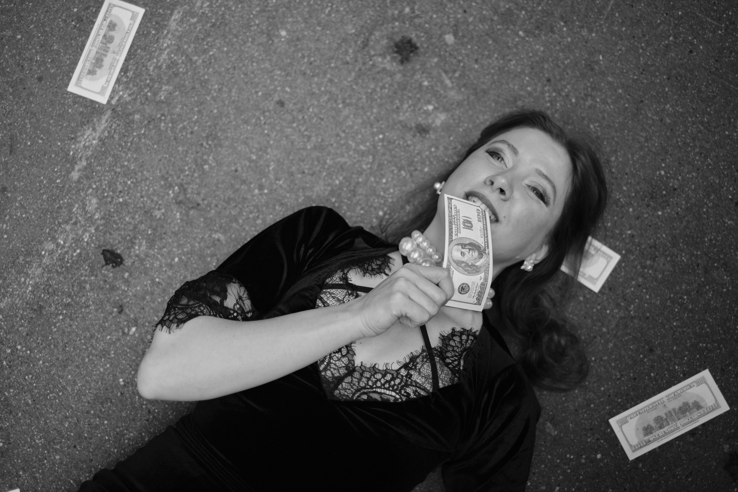 Девушка лежит на асфальте с деньгами