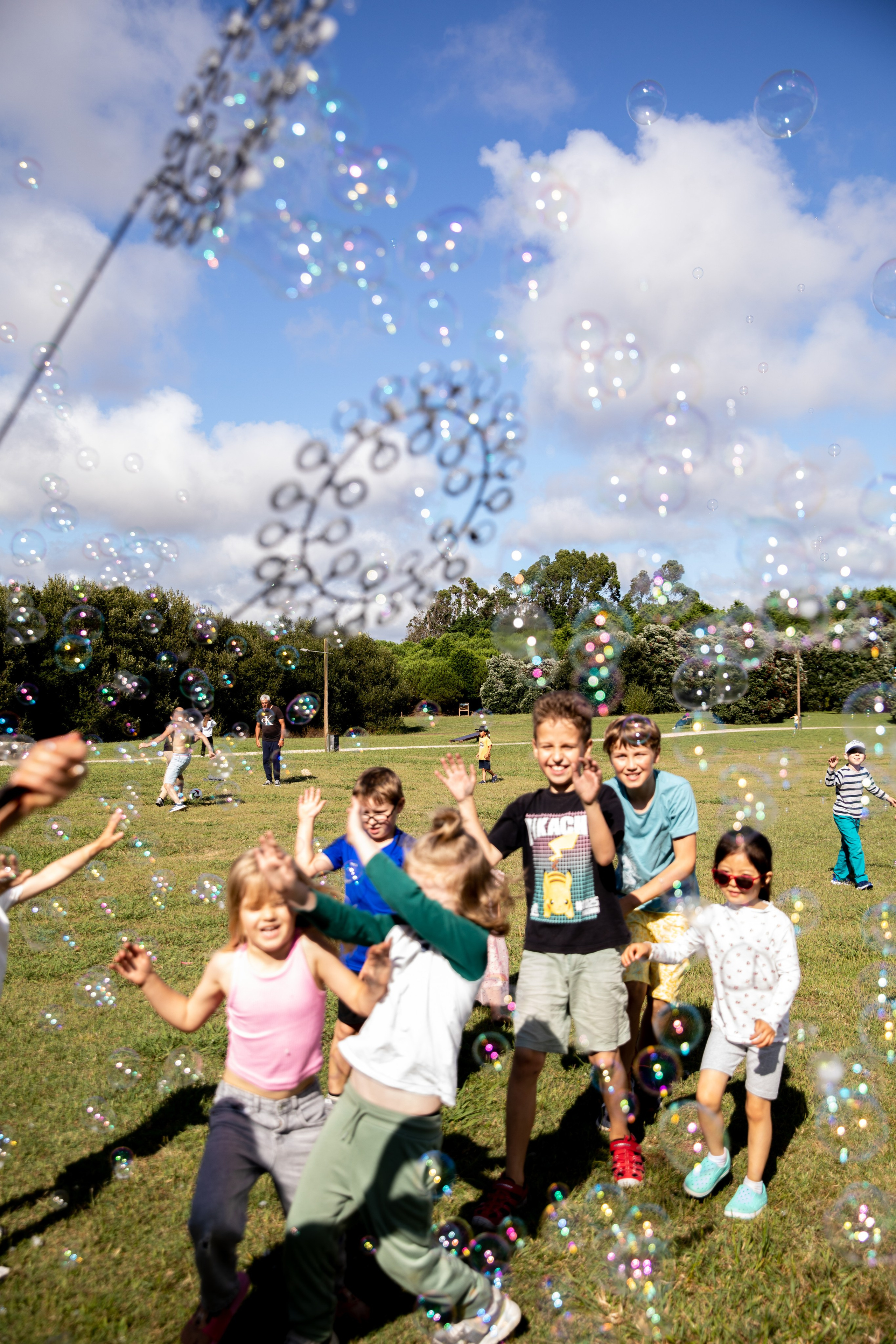 Smiling kids playing and blowing soap bubbles at a birthday photo shoot in the park