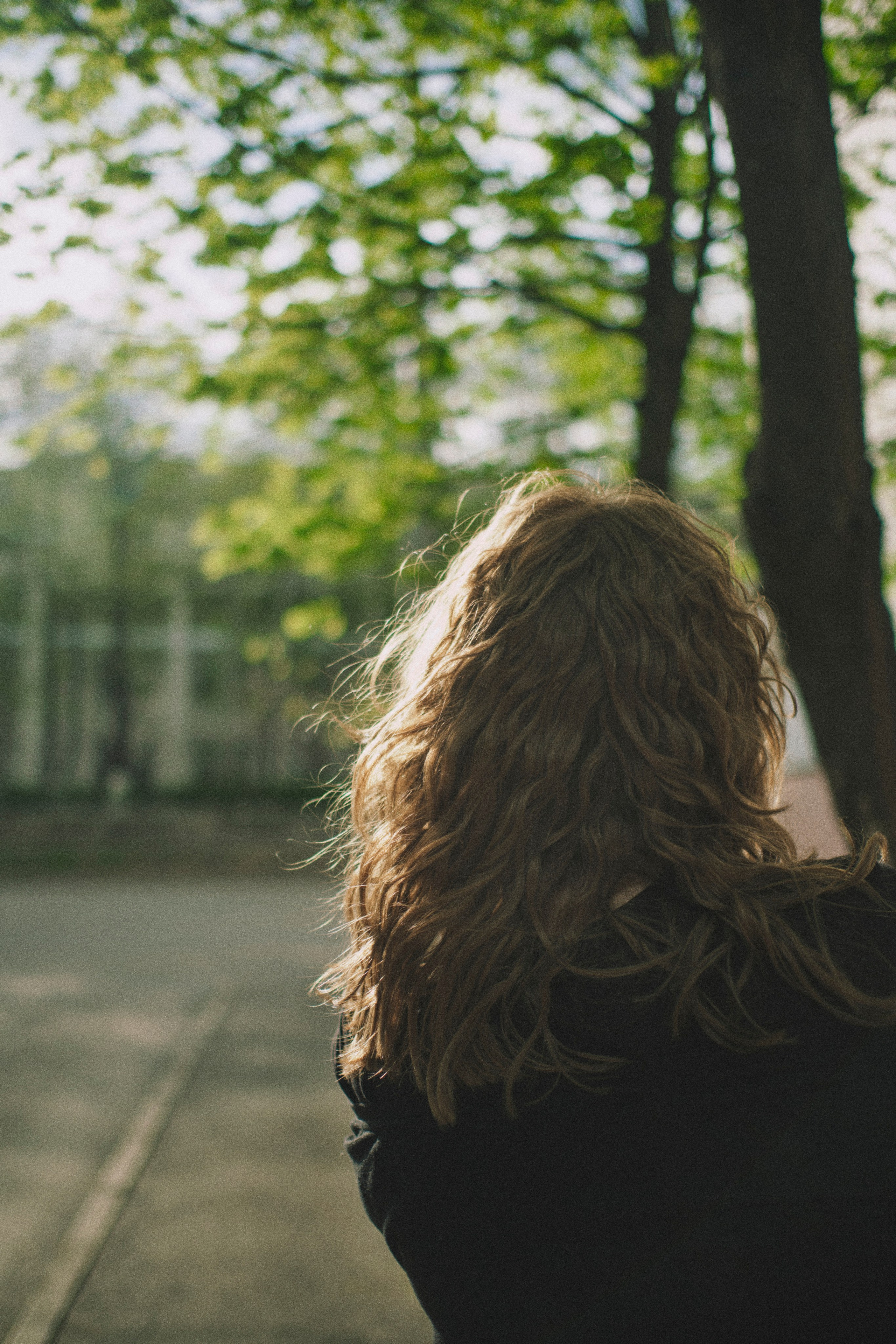 Свет падает на волосы женщины на фоне красивых деревьев