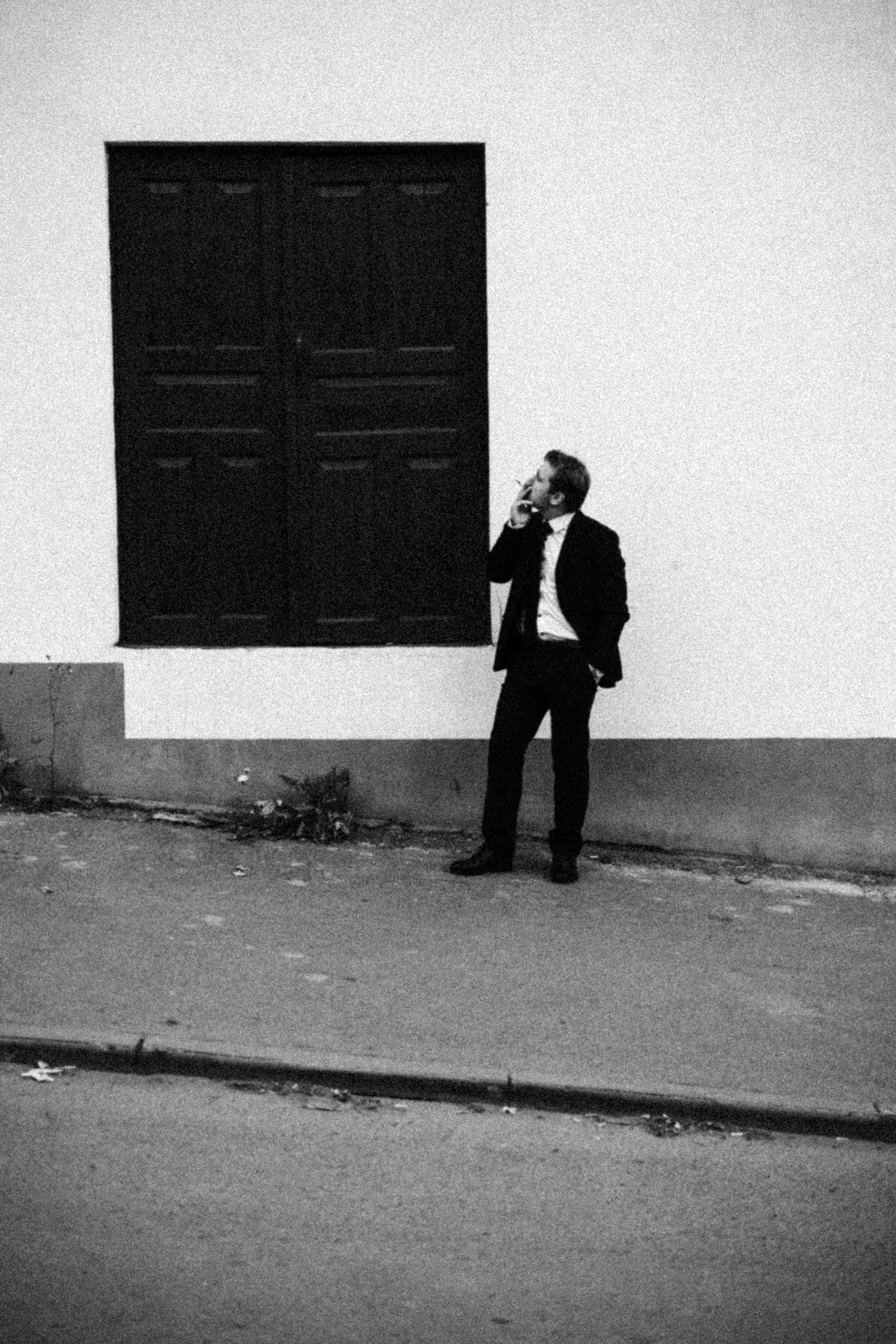 Мужчина ждёт кого-то у входа и курит