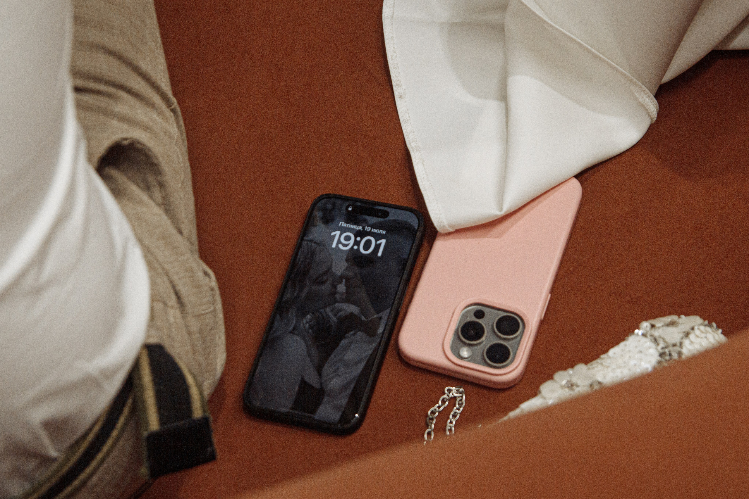 Телефон, ключи и аксессуары рядом с платьем невесты — детали свадебного утра.