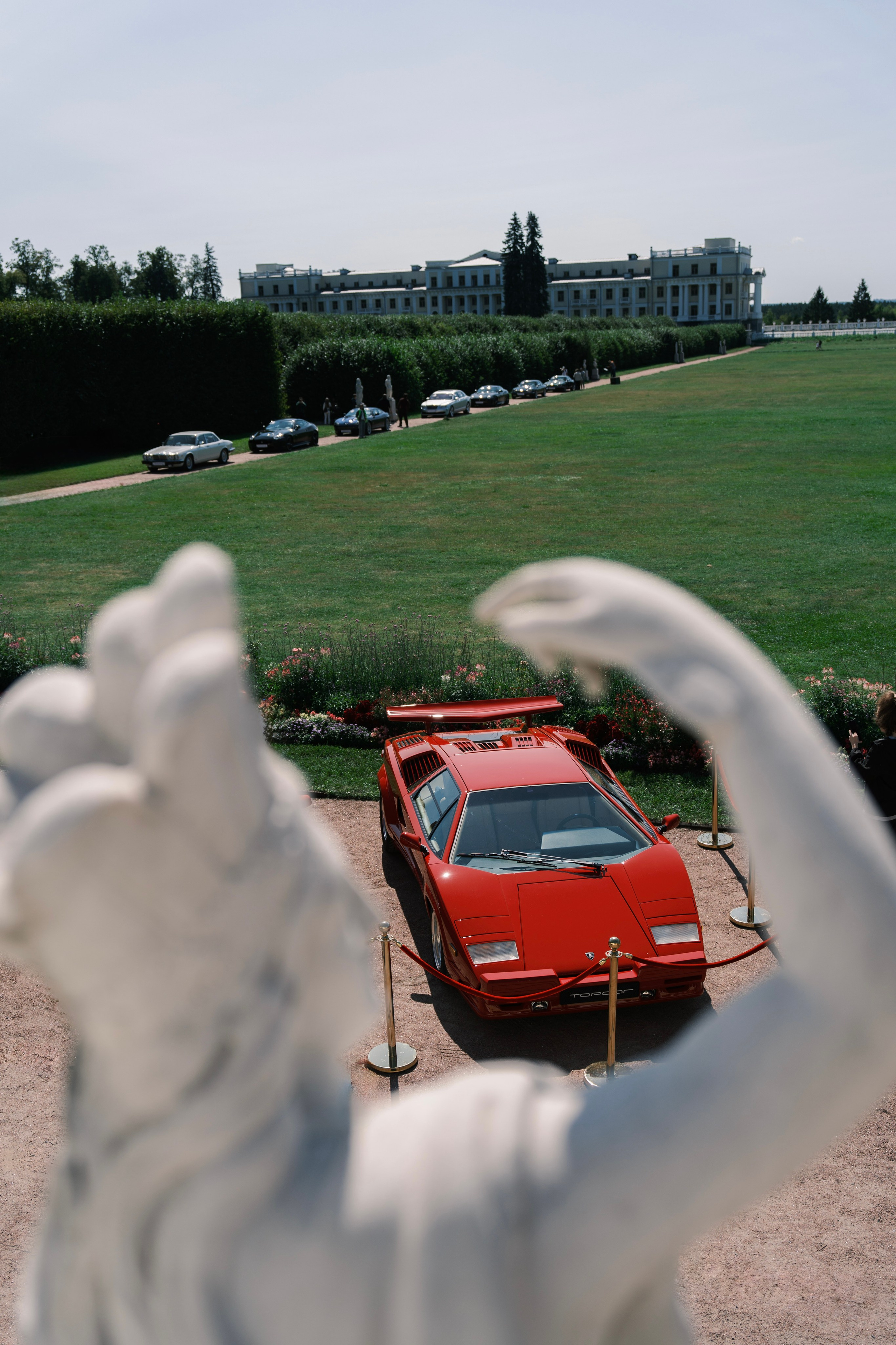 Оранжевый Lamborghini Countach в обрамлении садовой скульптуры